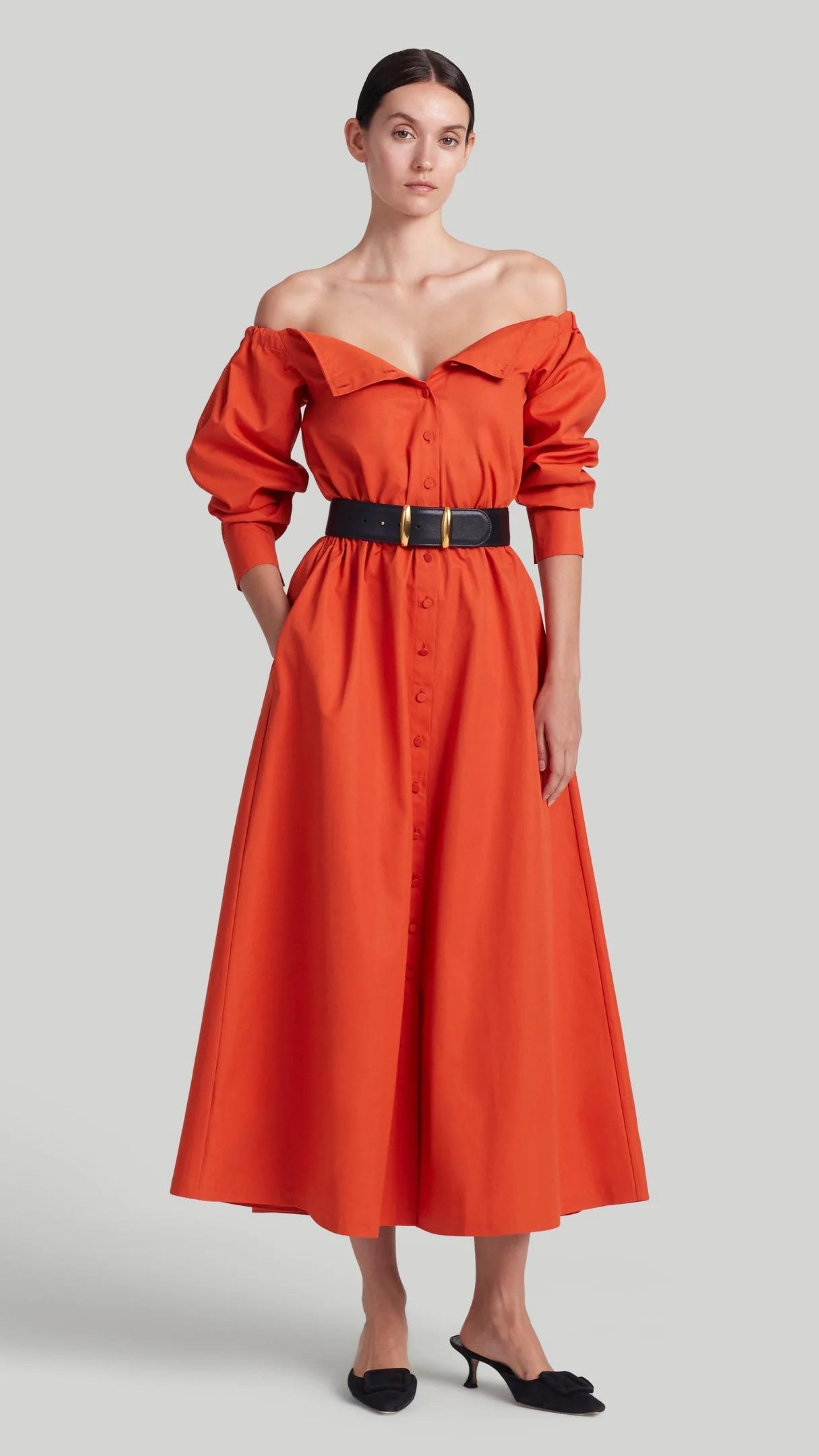 Altuzarra Zora dress shirt dress style soft cotton midi dress in red orange color. Made in Italy. The dress has off the shoulder neckline, puff sleeves and an elasticated waist waistband. Shown on model facing front
