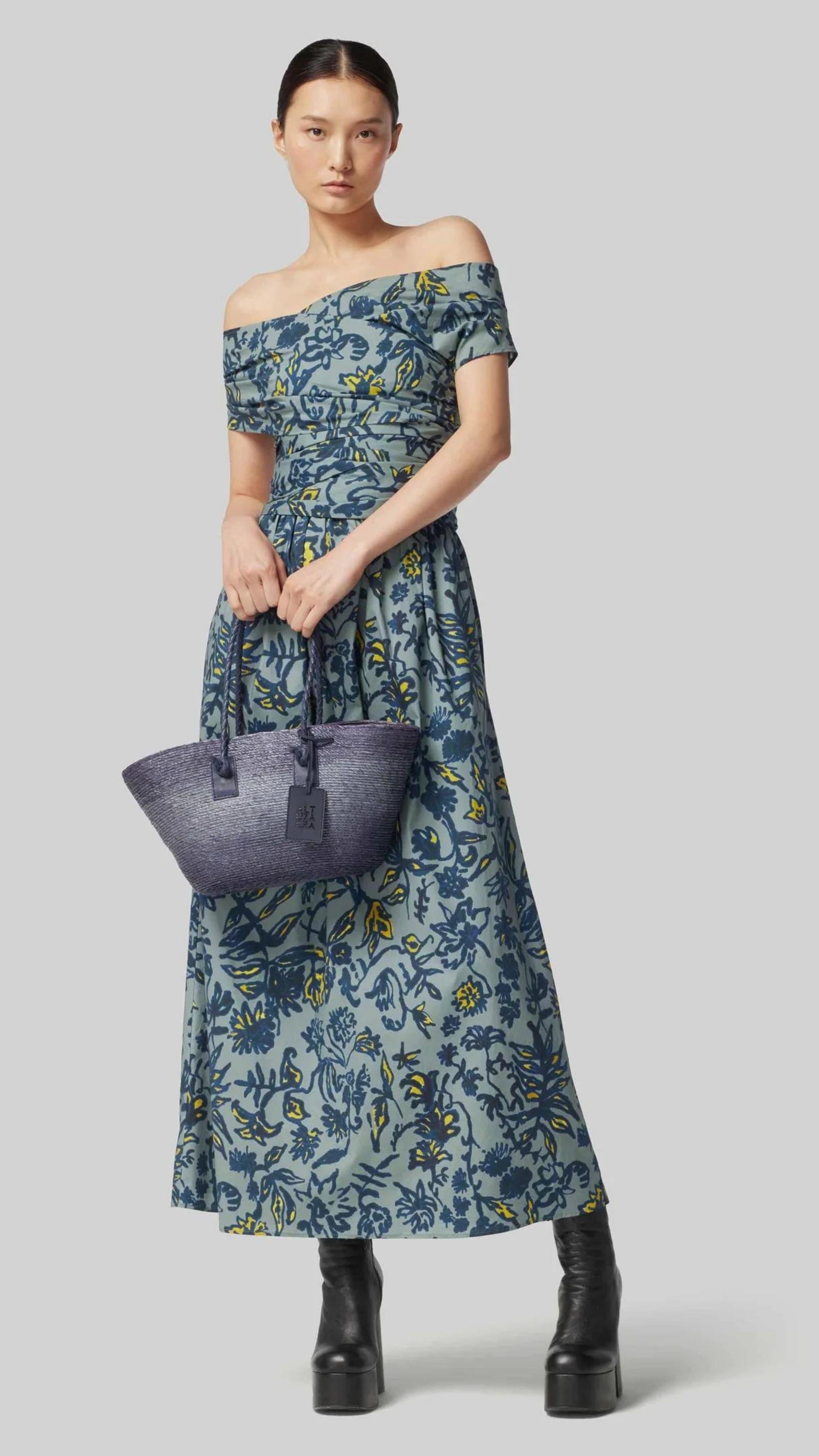 Altuzarra Corfu Dress in Stormcloud Shibori Flower. Relaxed off the shoulder cotton dress in beautiful grey blue, dark blue and yellow floral pattern. Wrap around style top with wrap around belt flows into the straight midi length skirt. Shown on model facing front. Available at experience 27 in madrid spain.