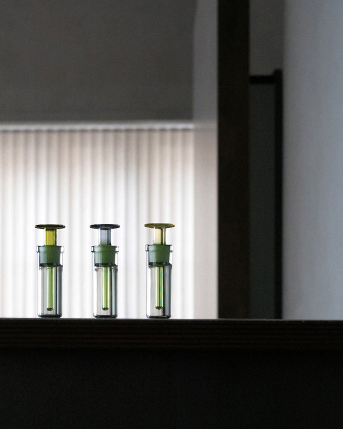 ARPA Piel 04 hand-blown glass bottles arranged in a dark architectural display