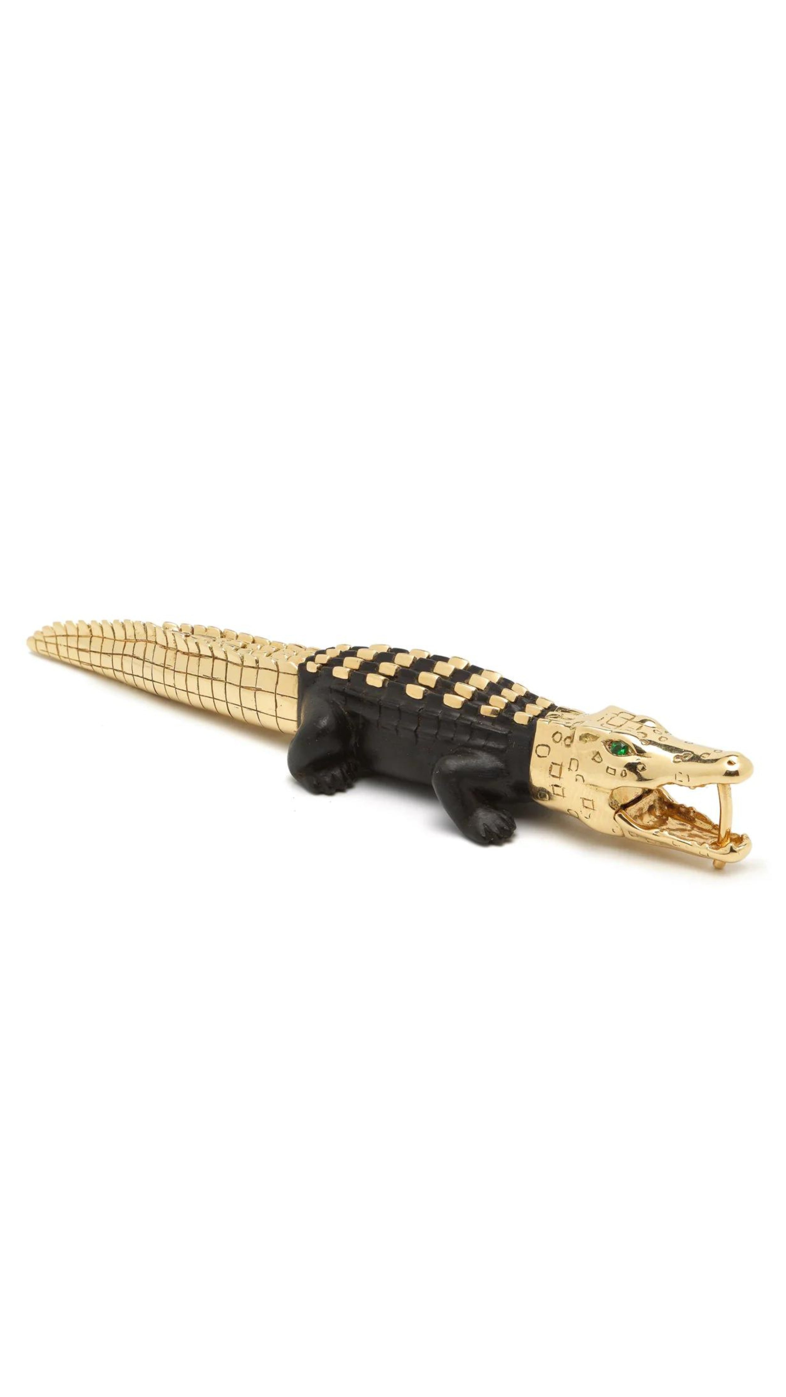 Bibi van der Velden, Ebony Wood Large Alligator Bite Earring with Studs. Crafted in 18K Gold and with an ebony wood body in the shape of an alligator. The gold head is highlighted with green tsavorite stones. The tail is gold scaled. Shown from the side view sitting.