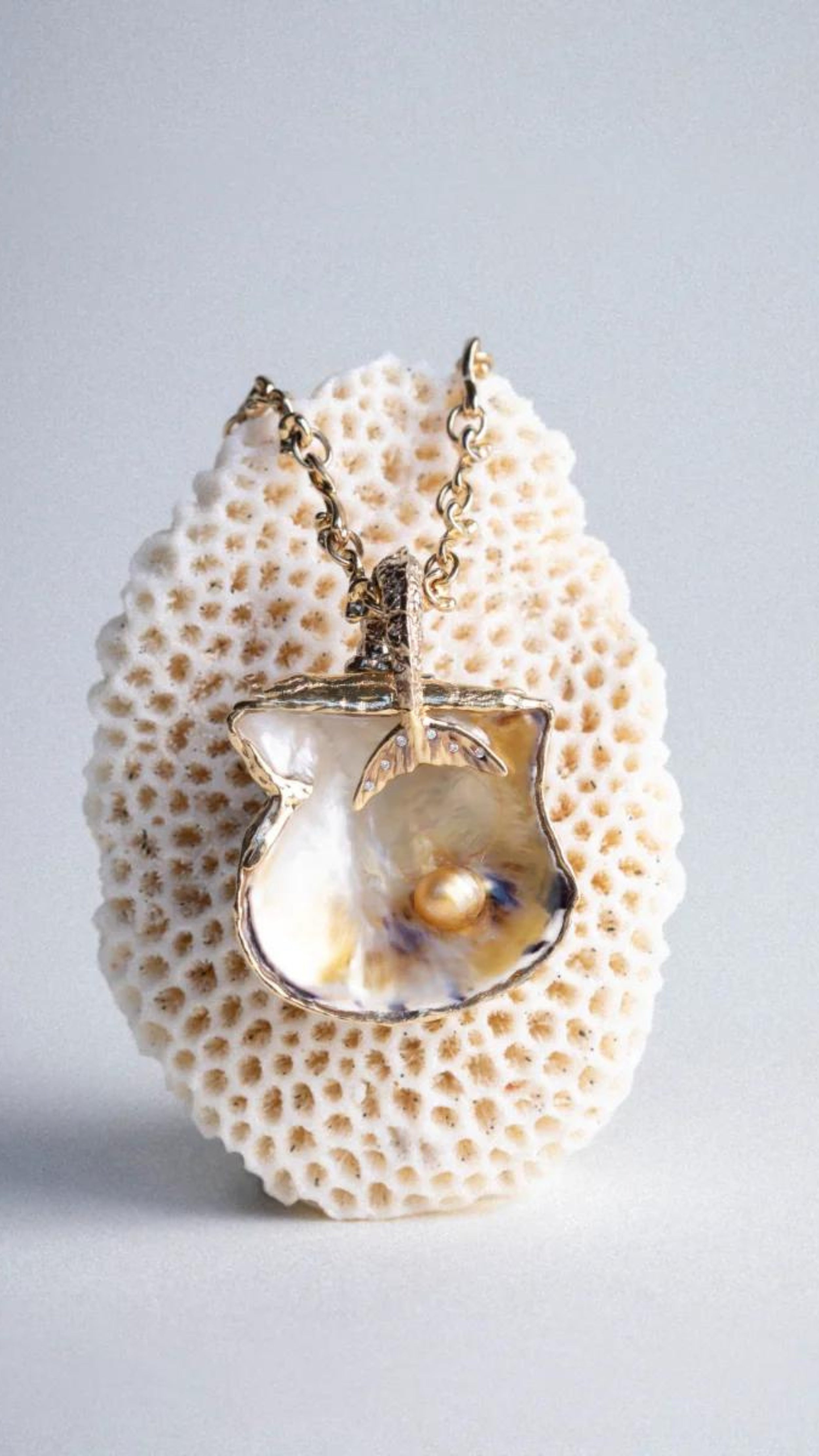 Bibi van der Velden Lagoon Shell Pendant with Wave Chain. 18k yellow gold shell shaped pendant showcases an iridescent pipe pearl for a shimmering effect. With a white diamond and a cream pearl on the interior and a wave chain crafted from 18k yellow gold.