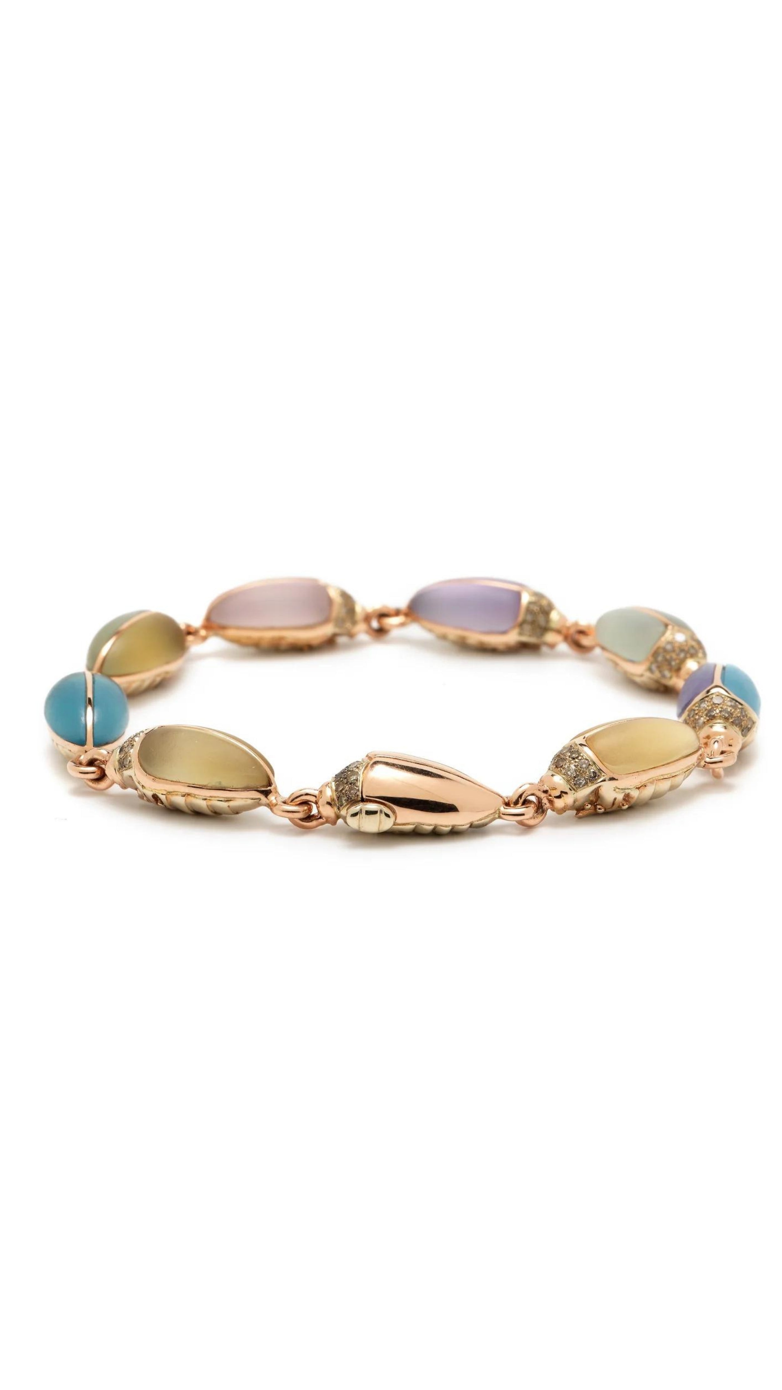 Bibi van der Velden Mini Scarab Eternity Bracelet. Made in 18k rose gold, this bracelet has nine  scarab beetles, each made with translucent, matte gemstones in soft shades. The beetles&#39; heads are paved with pale brown diamonds. Shown from the side view.