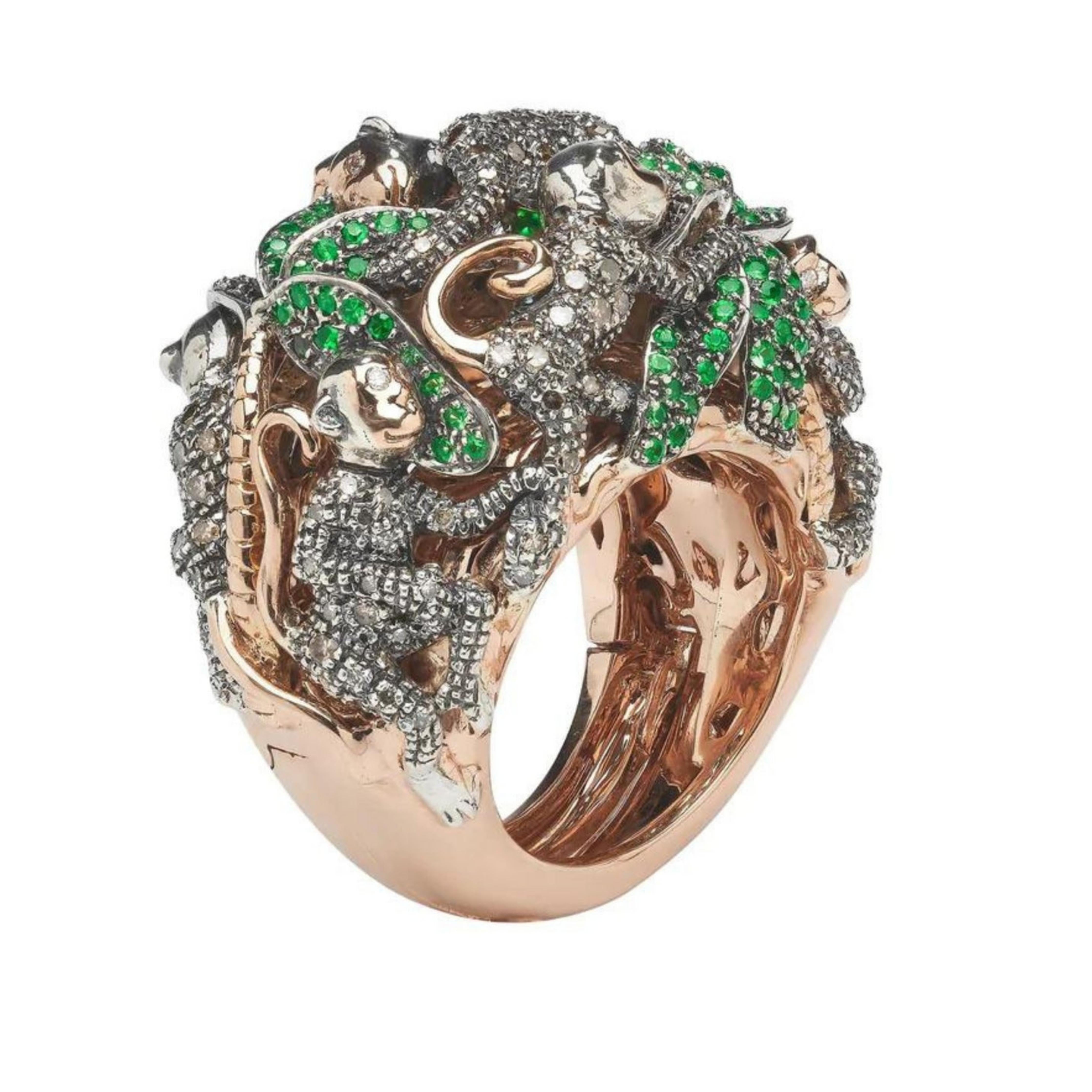 Bibi van der Velden, Monkey Ring in a Ring. A two part ring, crafted from 18K rose and yellow gold and sterling silver, this ornate cocktail ring is artfully embellished with brown diamonds and sparkling green tsavorites. The cocktail ring is topped with a family of jewelled monkeys nestled amongst lush palm trees. A secret compartment opens and reveals the 18K gold banana ring inside. Shown from side.