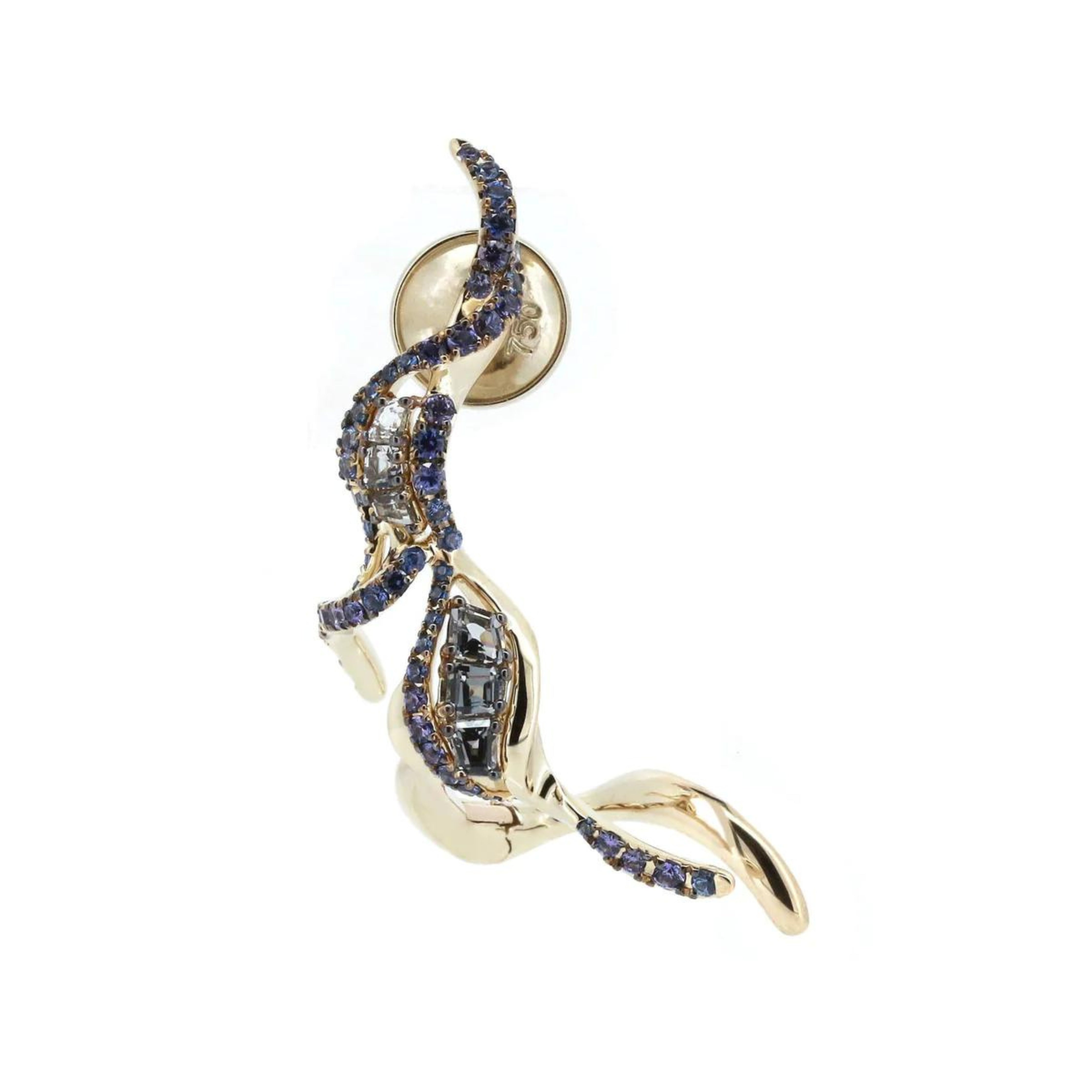 Bibi van der Velden Puff Ear Climber in Blue Sapphire. shades of blue and grey sapphires and spinels adorn the Puff Ear Climber's 18k white gold tendrils. Delicately crafted, this climber elegantly pierces the ear lobe and sweeps up the ear's outer edge. Product shown from the front view.