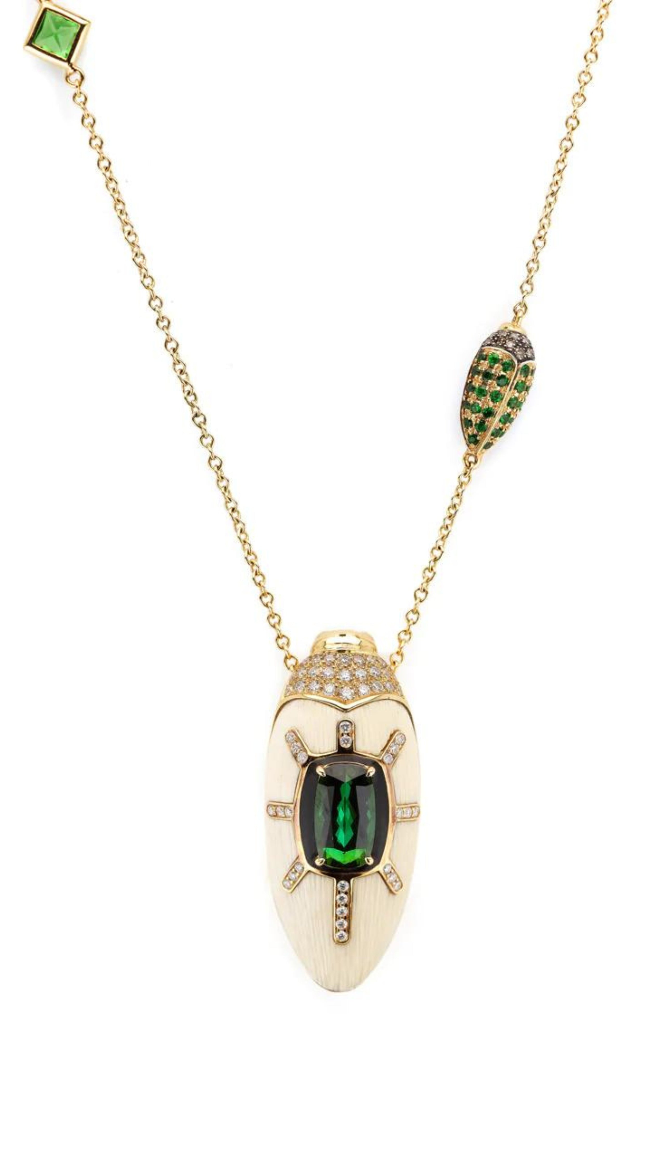 Bibi van der Velden Scarab Mammoth Necklace. Art deco style scarab pendant drop crafted from mammoth tusk and set with green tsavorite stones and pave white and brown diamonds. With links in the chain of scarabs and inset stones. Adjustable length necklace. Sustainable high jewelry. Photo showing a close up on the scarab pendent.