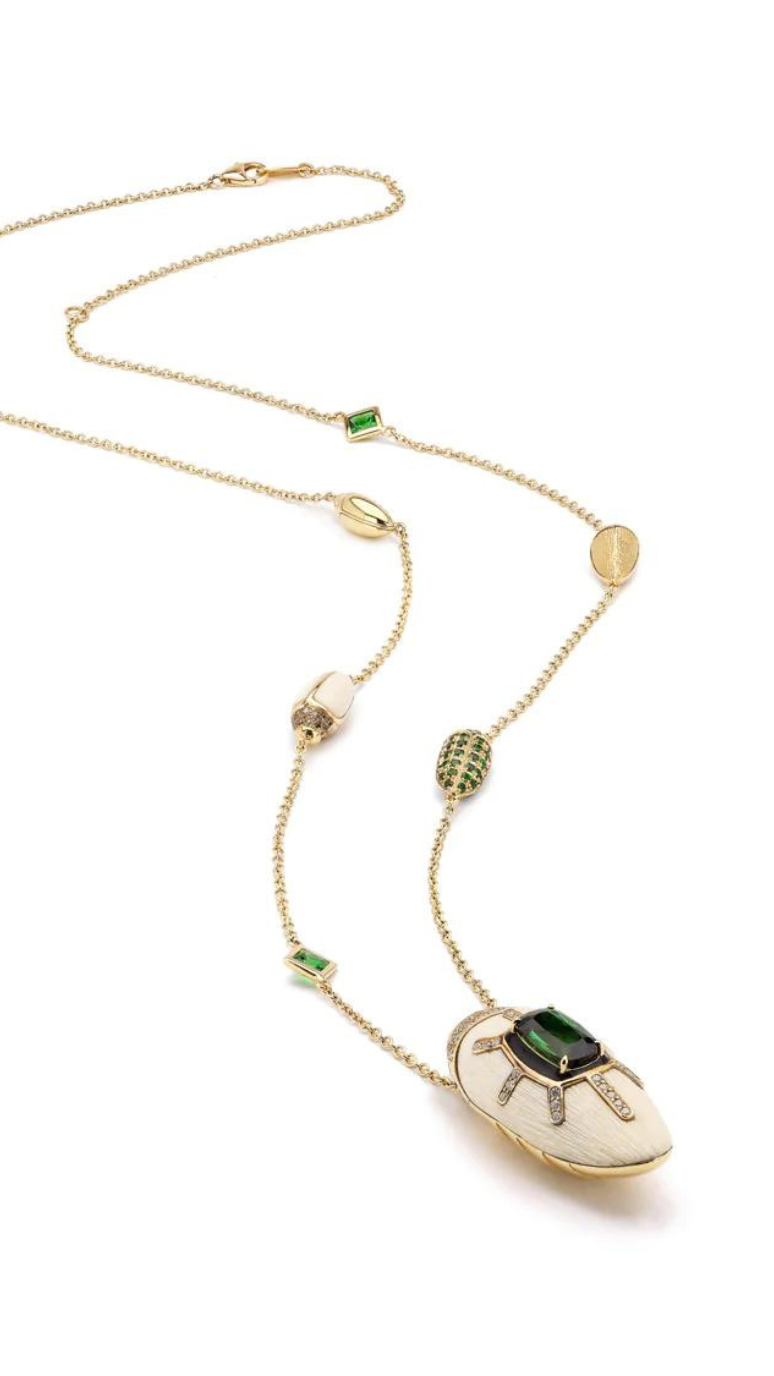 Bibi van der Velden Scarab Mammoth Necklace. Art deco style scarab pendant drop crafted from mammoth tusk and set with green tsavorite stones and pave white and brown diamonds. With links in the chain of scarabs and inset stones. Adjustable length necklace. Sustainable high jewelry. Photo showing the entire length of necklace from the side.