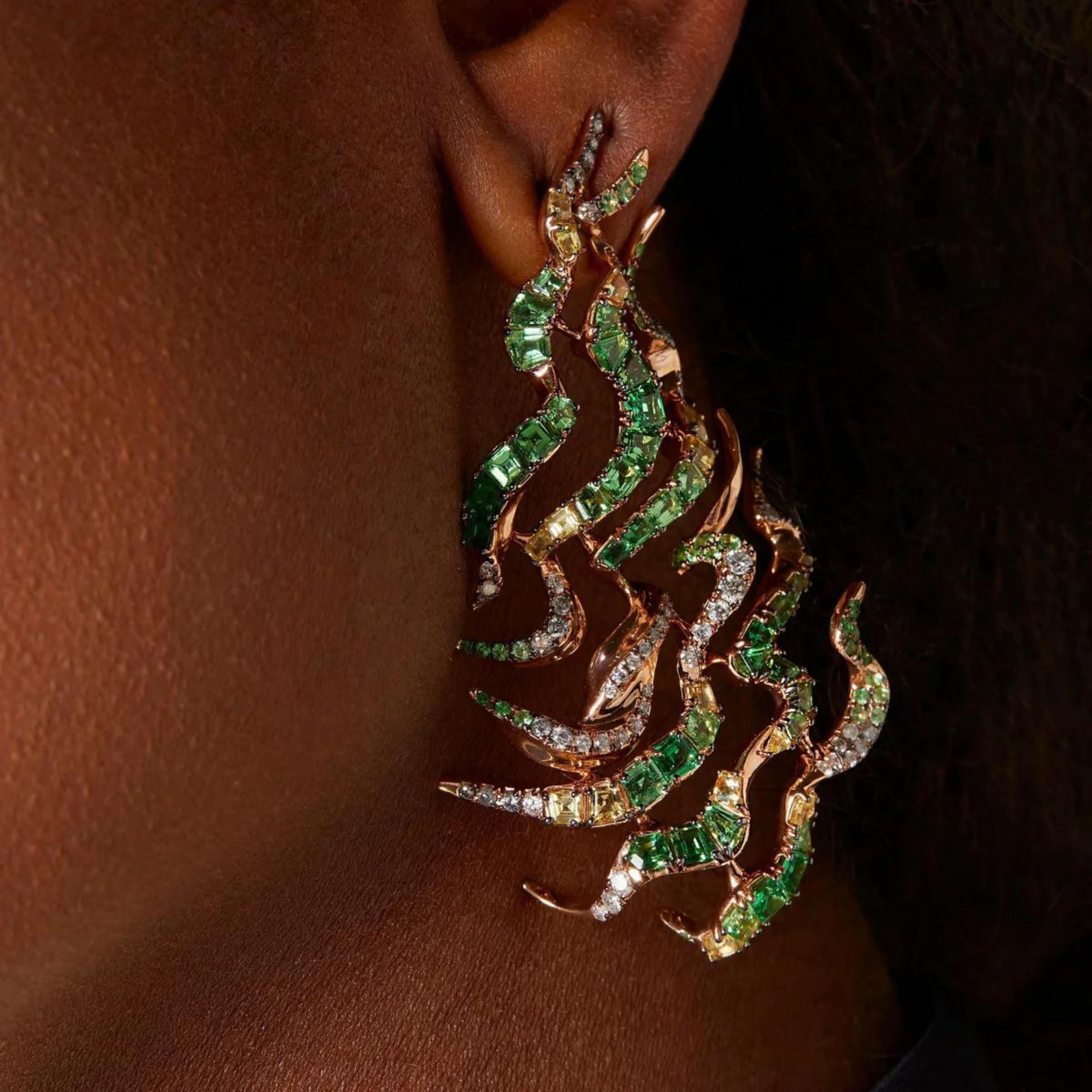 Bibi van der Velden Tsavorite Single Smoke Haze Earring. Crafted from multiple tsavorites, white and grey diamonds, and yellow sapphires and set in 18K Rose Gold this single earring invokes the beauty of a swirling haze of smoke. Shown on model.