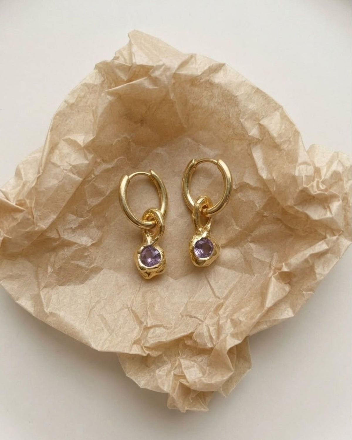 18k gold vermeil amethyst drop earrings resting on brown tissue paper