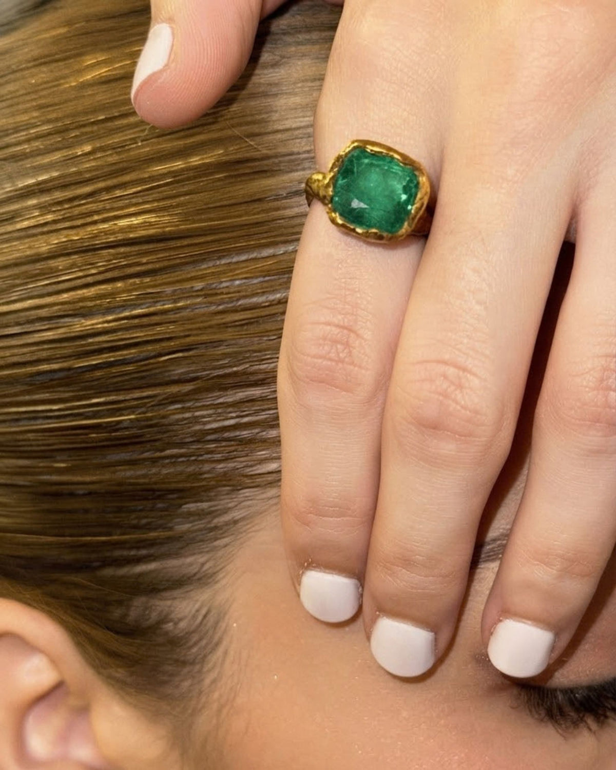 Close-up of an 18k gold vermeil emerald ring worn on a model's finger