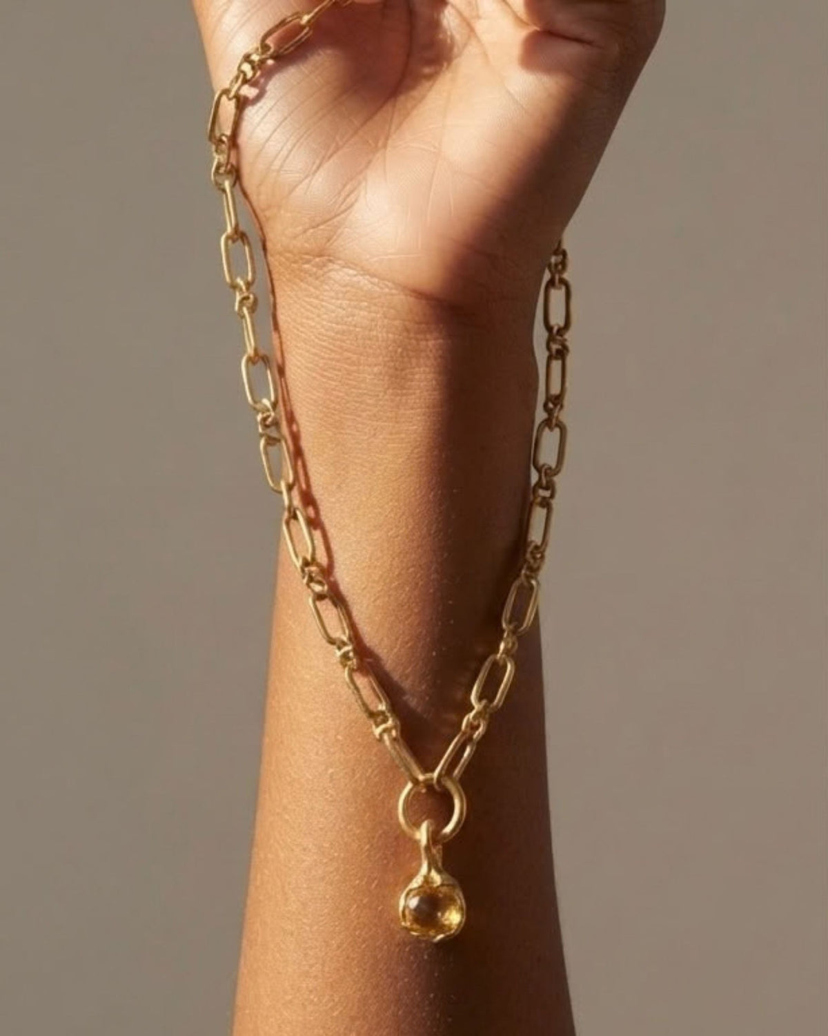 18k gold vermeil necklace with a green gold quartz pendant draped over a model's wrist