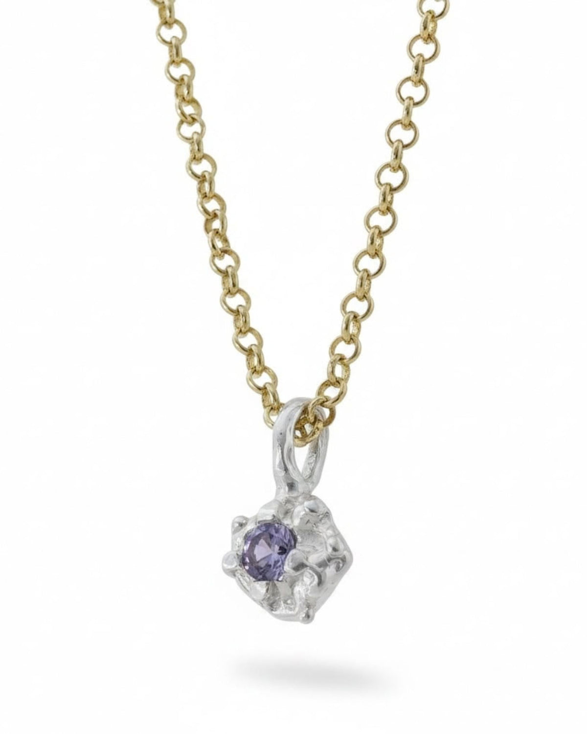 Close-up of a sterling silver pendant with a lab-created amethyst stone on a gold chain, on white background