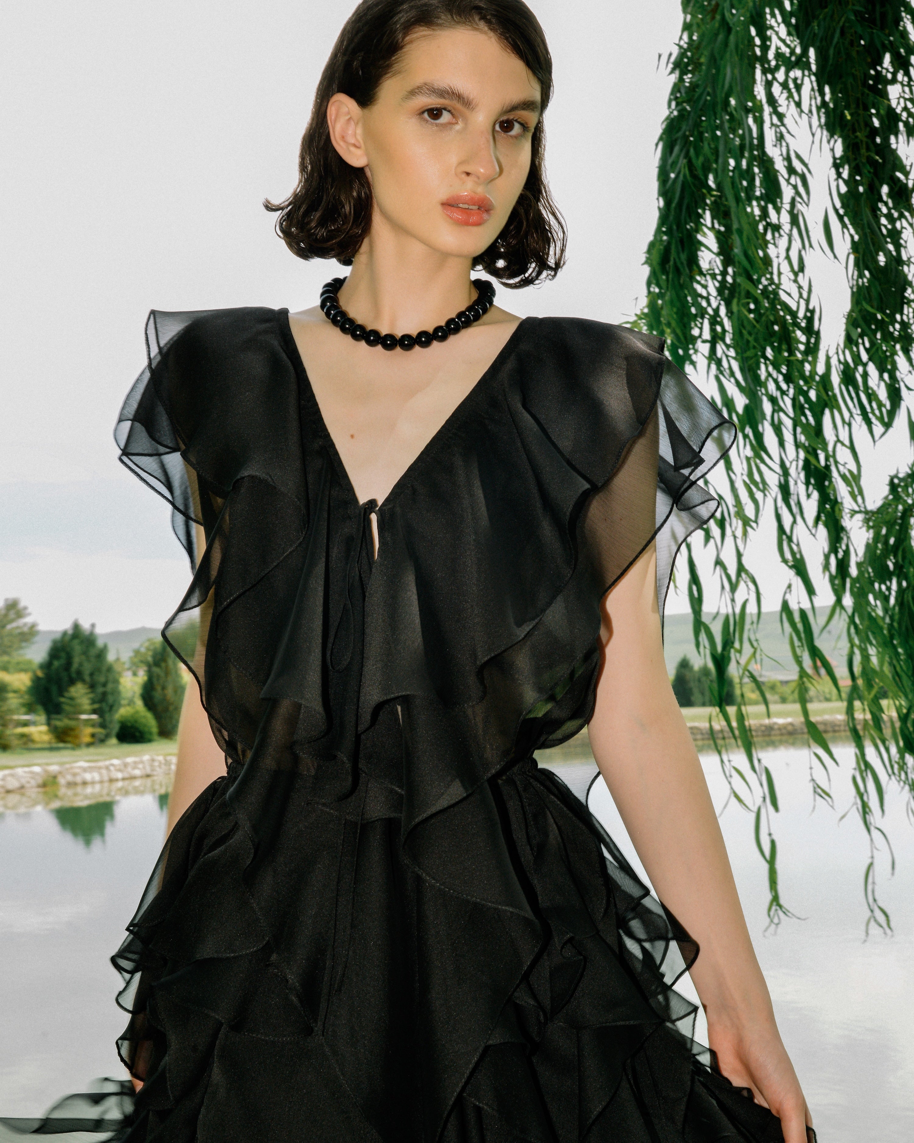 Model wearing the Ondy Dress by Lalo Cardigans, a black silk ruffled dress with a flowing silhouette