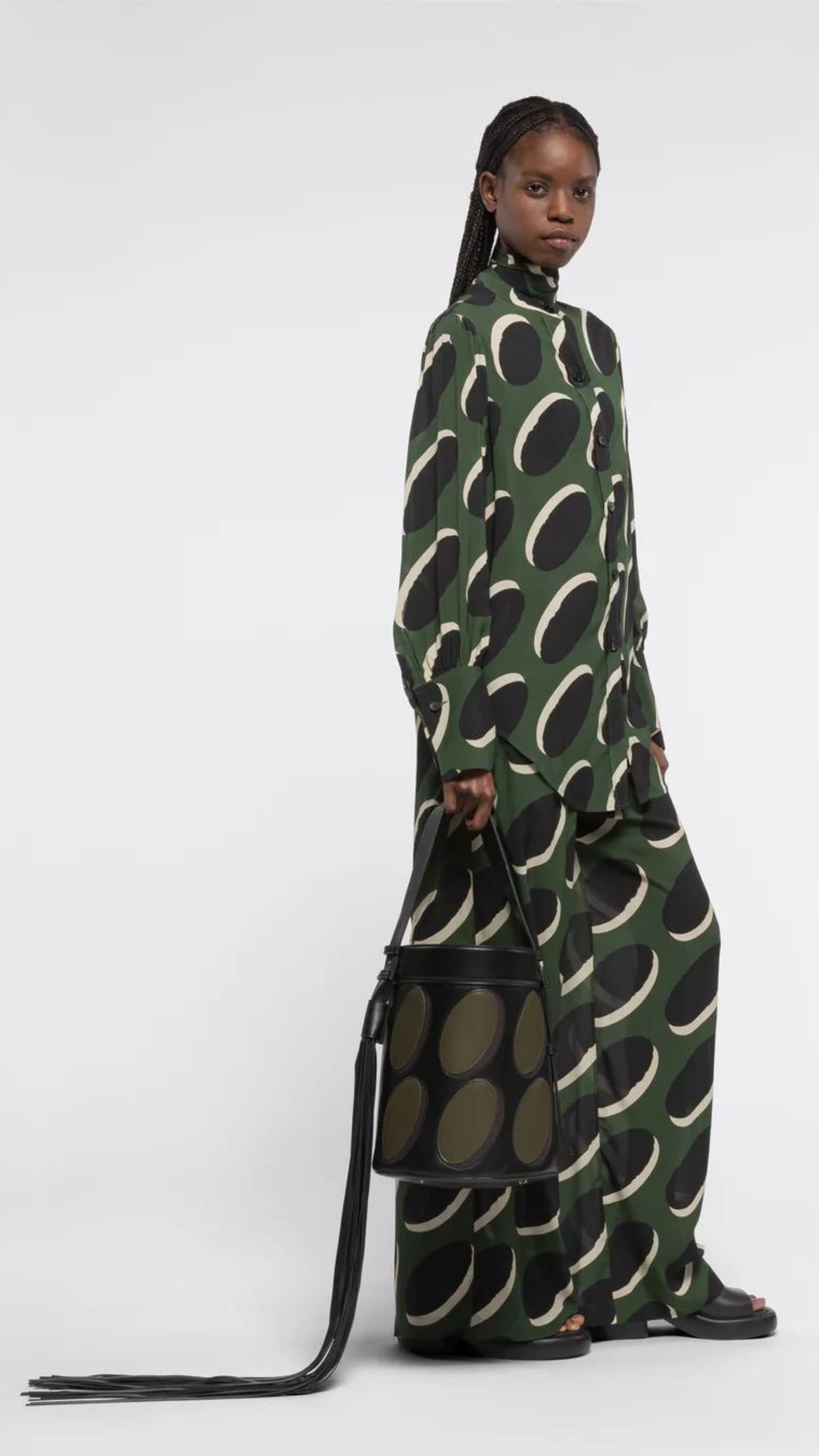 AZ Factory Colville Molly Molloy Lucinda Chambers,  Leather Patchwork Midi Bucket Bag.. Black oval bucket back in black leather with olive green ovals patches. Has an adjustable black handle and a dramatic oversize black leather tassel. Product shown with a model.