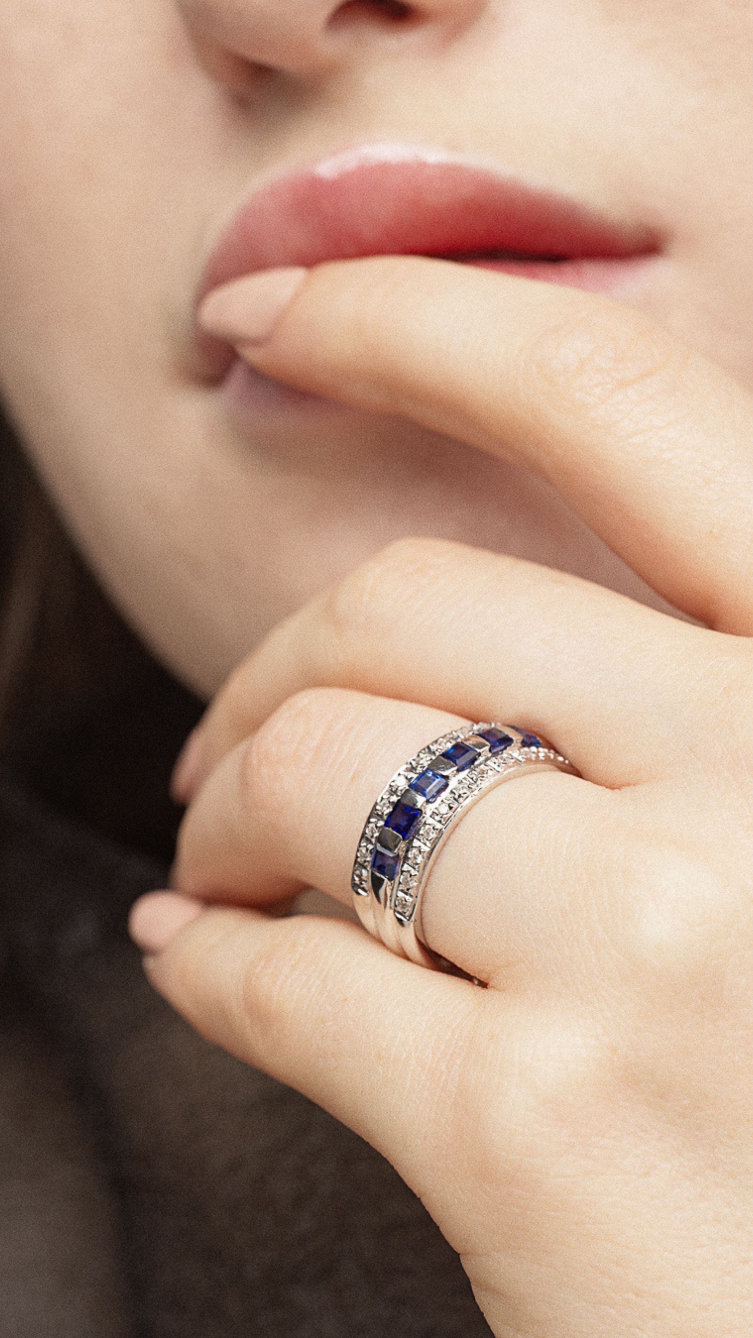 Conde de diamante Azura Ring. 18K white gold band ring with a center row of carré cut blue sapphires flanked on each side by bands of pave white diamonds. Shown on model facing front.