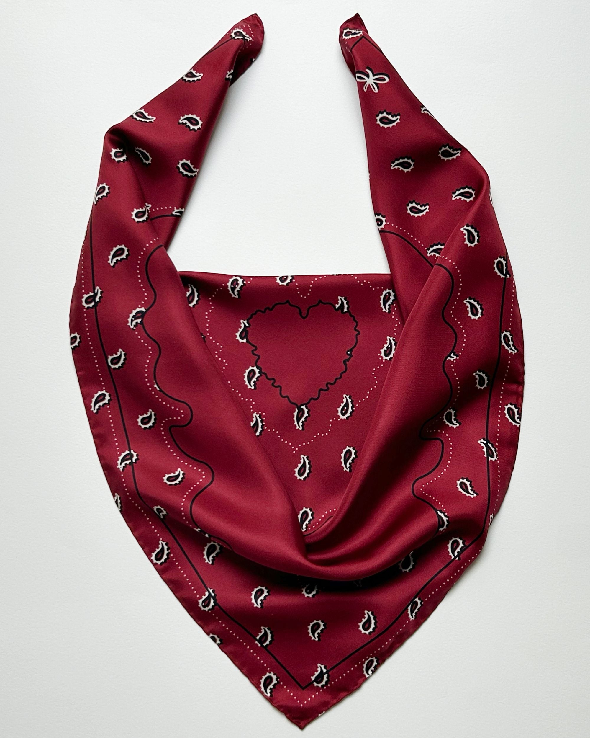 Square red silk scarf laid flat with bandana pattern