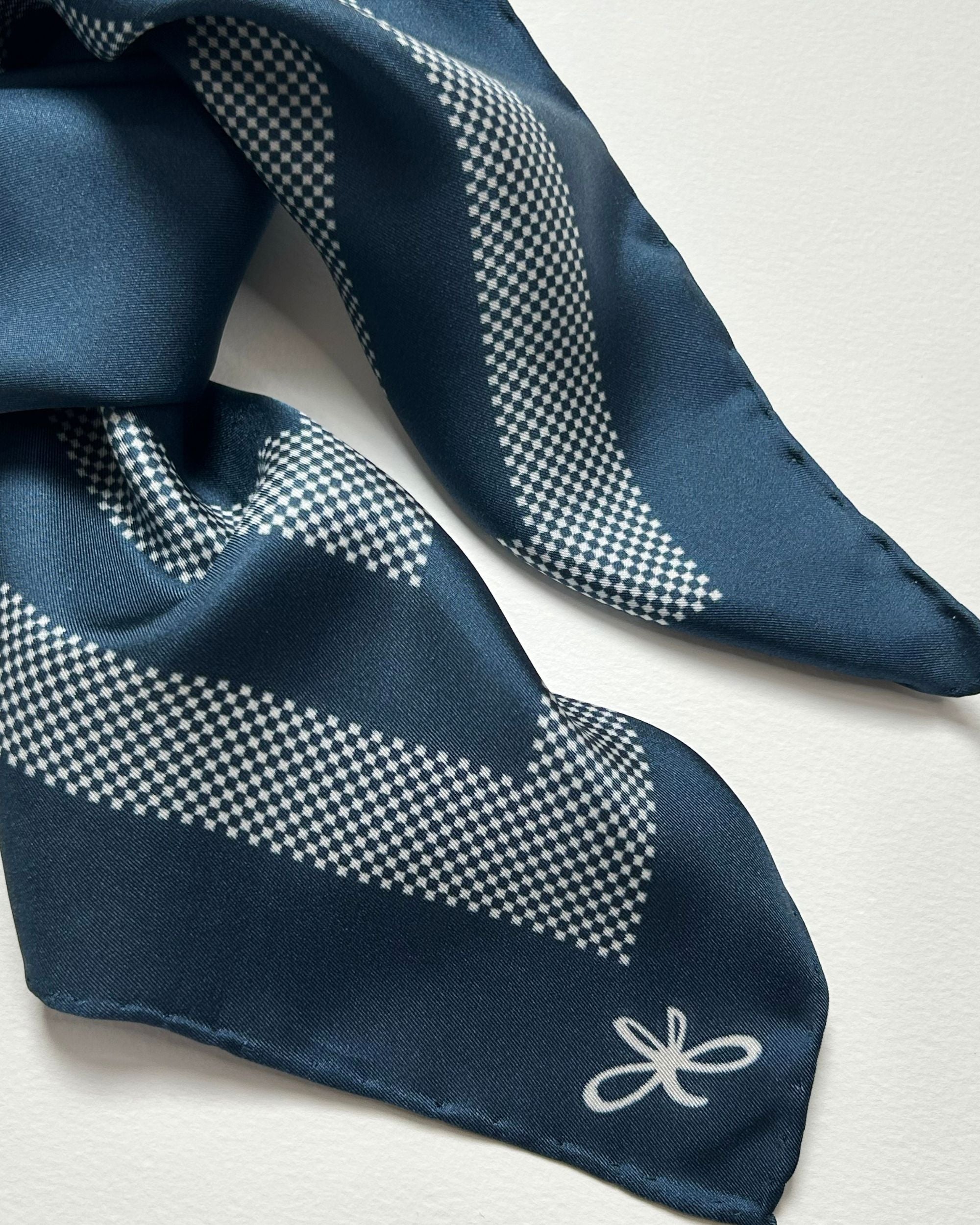Blue silk scarf tied showing border detail and logo
