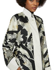 For Restless Sleepers Agrio Silk Top in Black and Ivory. Crafted from silk twill with a deconstructed border and a Korean collar, this coat is finished with a striking black and ivory pattern, highlighted by wide ivory borders at the collar, hem, and cuffs. Shown in model close up front facing.
