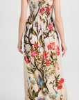 For Restless Sleepers Arpocrate Dress in Tree in Bloom Red. Ultra lightweight cotton summer dress with rouched elastic banded top and pleated maxi skirt. Elastic strap sleeves. Printed in a bright rose floral tree print with birds. Has pockets. Back view shown on model.