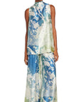 For Restless Sleepers Carcino Top. Sleeveless style in silk with blue and green tones. Japanese floral pattern in whire. Long style with adjustable scarf neckline. Shown on model facing front with coordinating Callisto Pants.