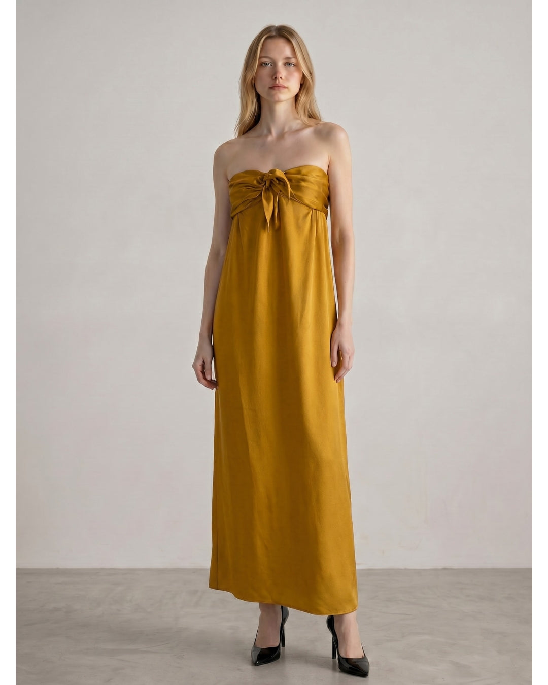 Model wearing Françoise Lucie Dress in amber gold silk, styled with black heels, full-length front view