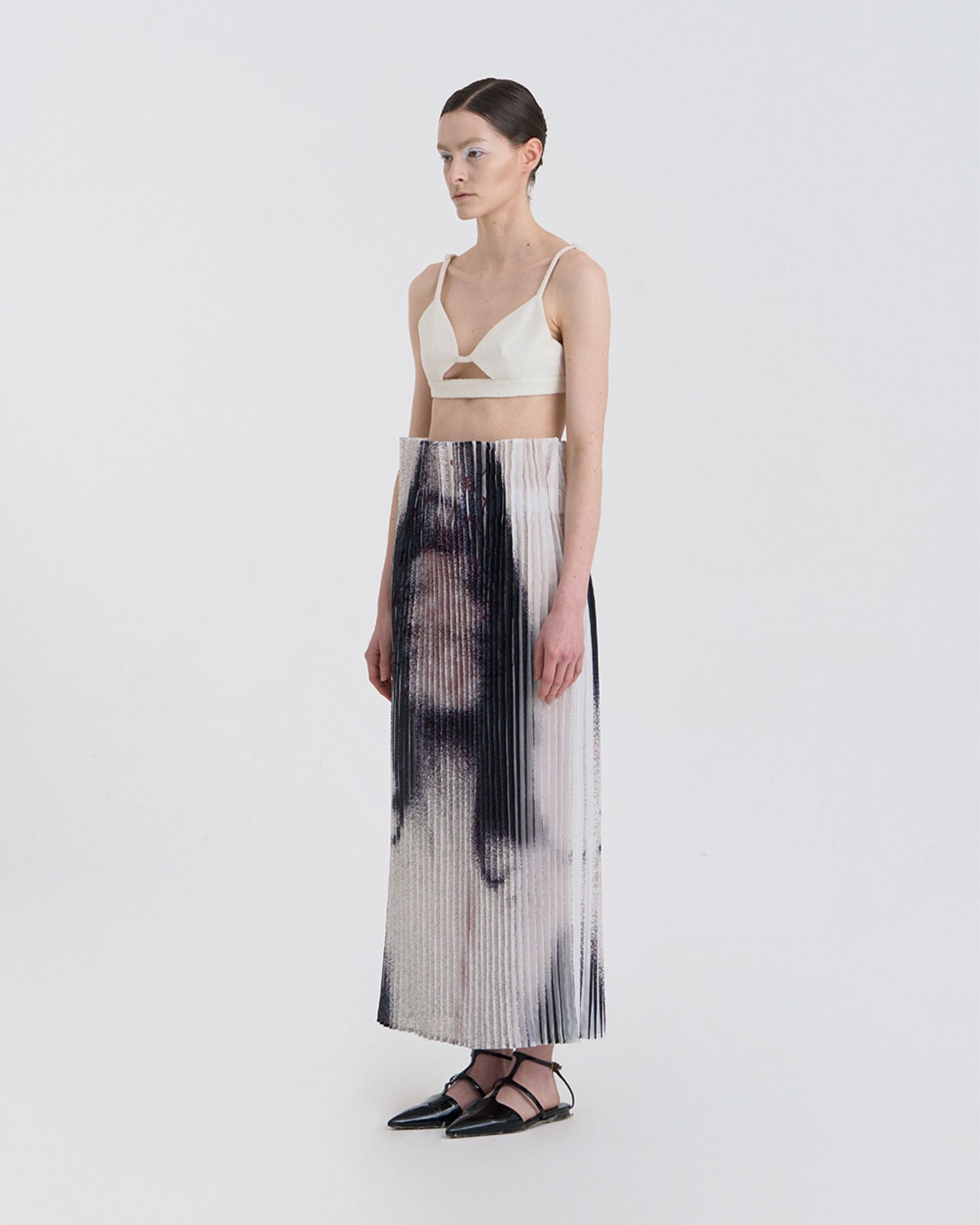 Angled view of JINSUN Anamo Pleated Skirt highlighting digital print and pleat texture.