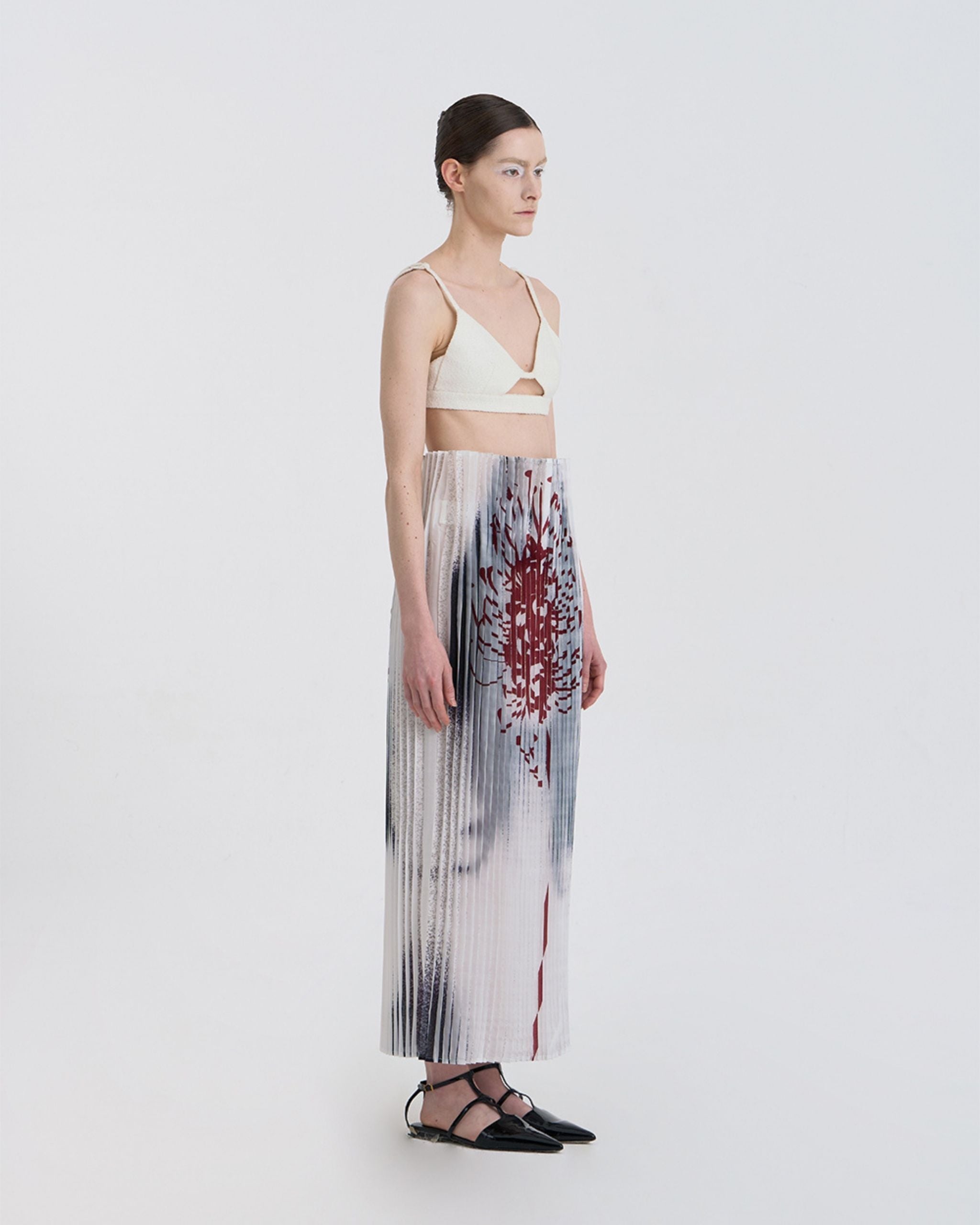 Angled view of JINSUN Anamo Pleated Skirt highlighting digital print and pleat texture.