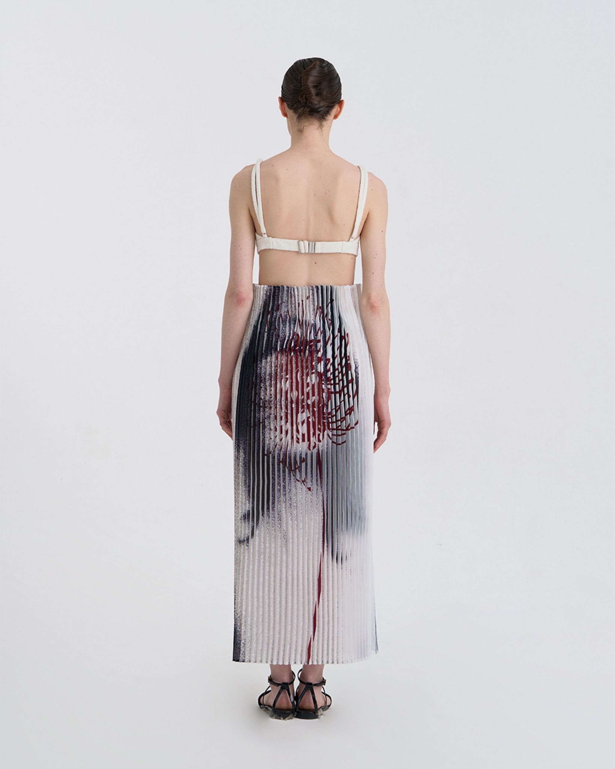 Back view of JINSUN Anamo Pleated Skirt with printed pattern continuing around waist and hem.