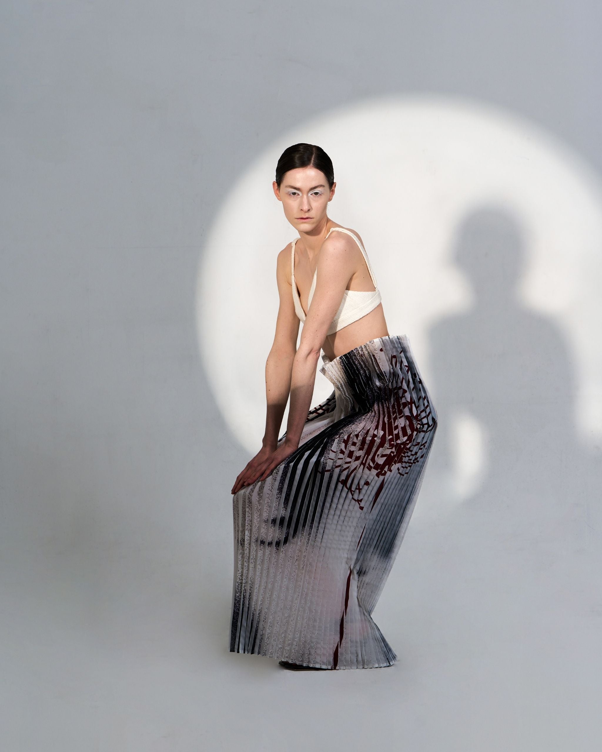 Editorial image of JINSUN Anamo Pleated Skirt photographed under soft light, emphasizing print and form.