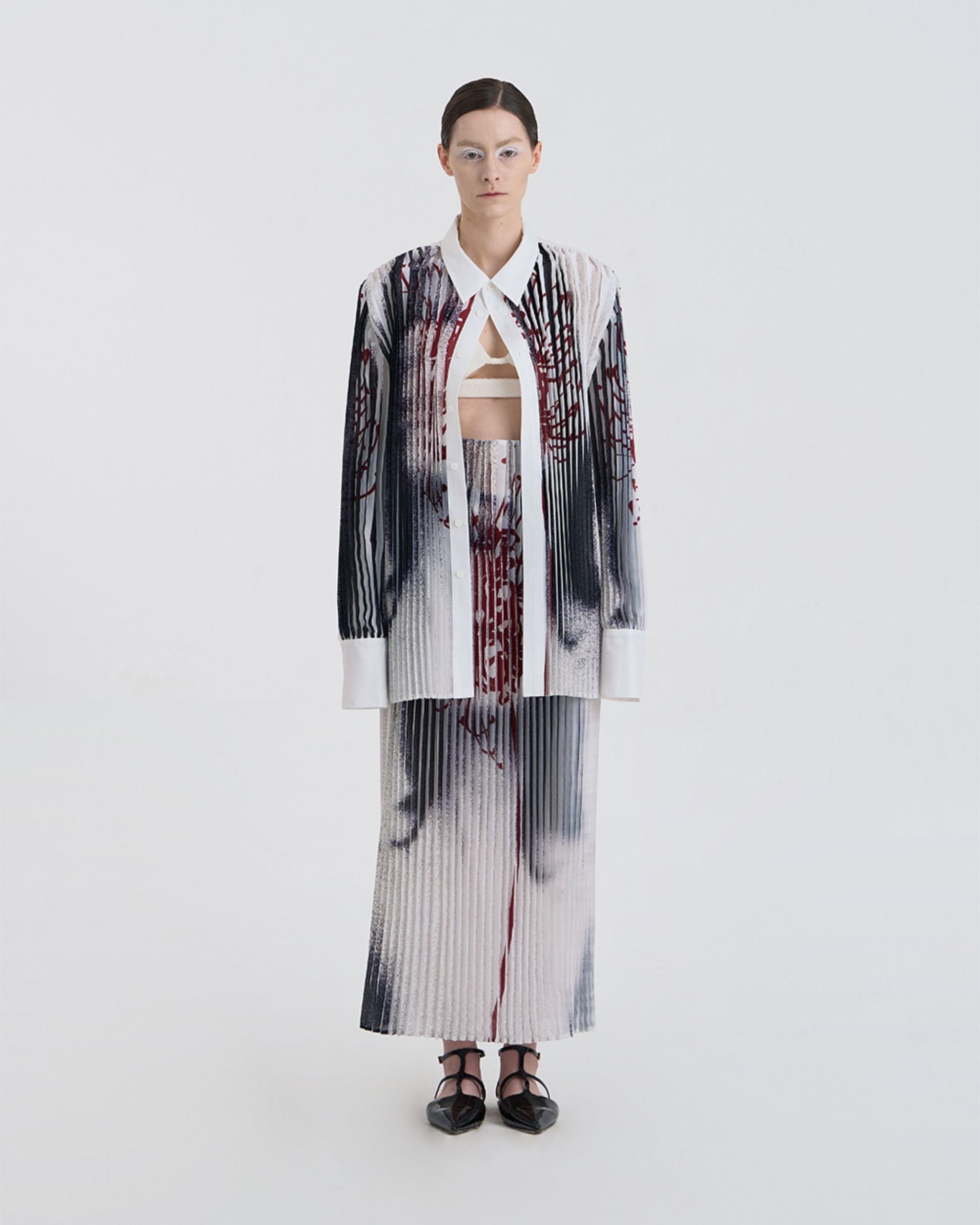 Front view of model wearing JINSUN Anamo Printed Shirt, pleated ivory fabric with abstract red and black print