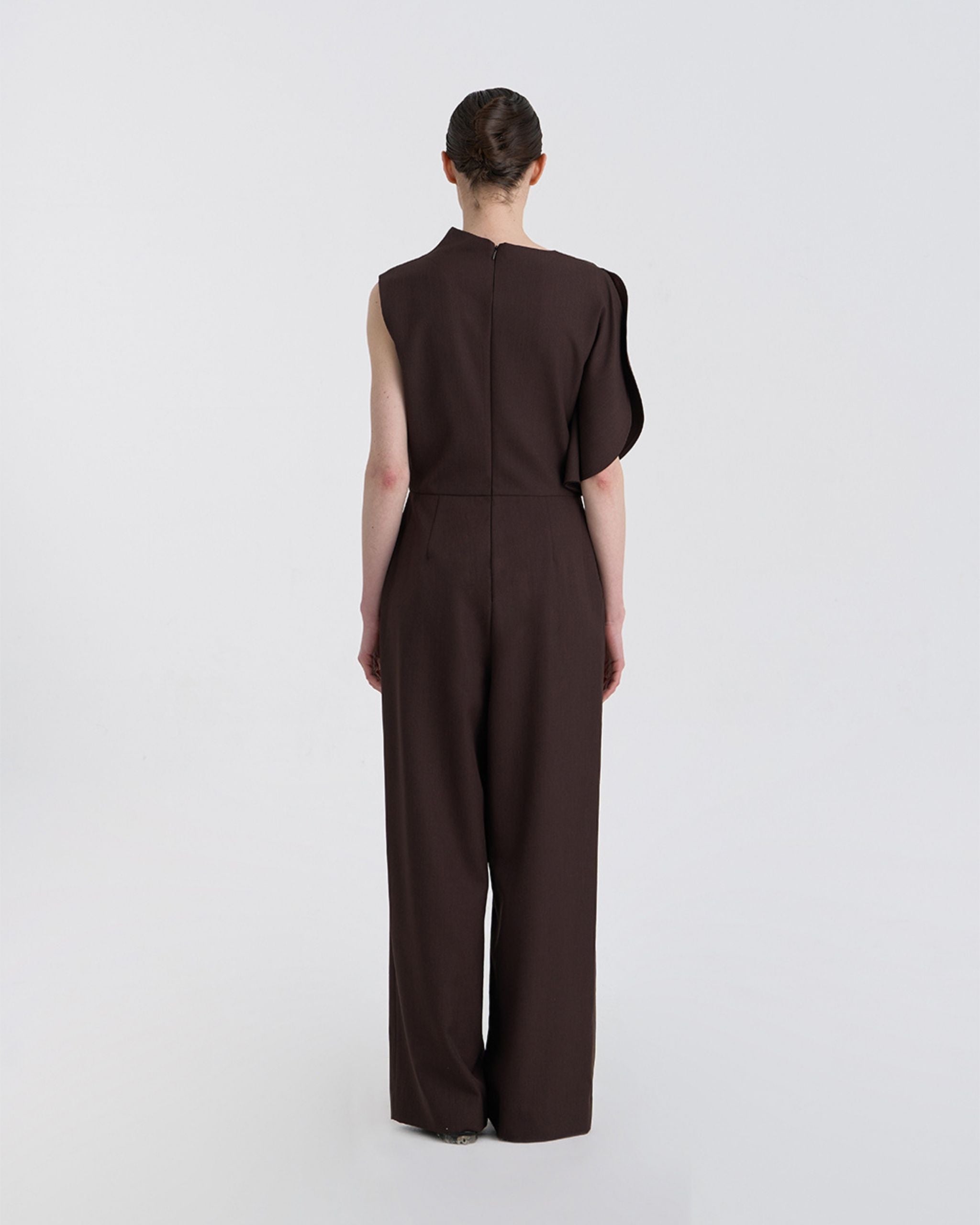 Back view of JINSUN Filante Wool Jumpsuit highlighting single draped shoulder