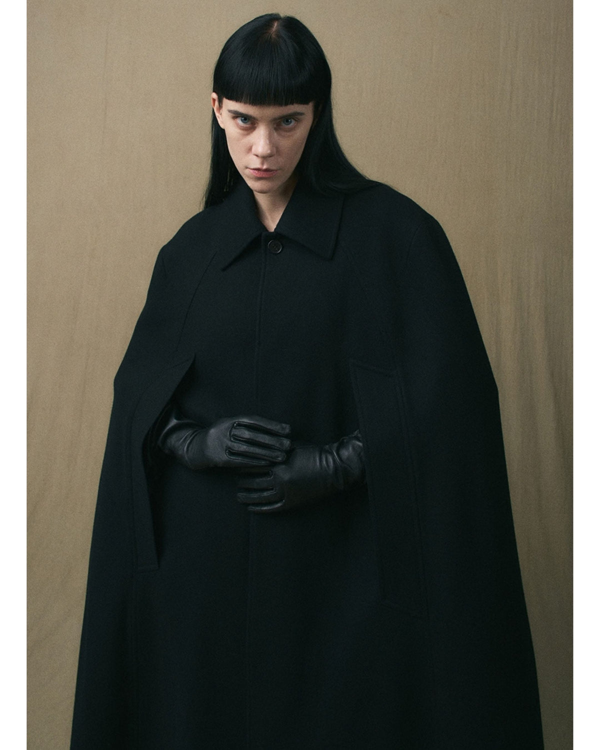 Close-up of the collar and concealed fastening on the black wool cape coat