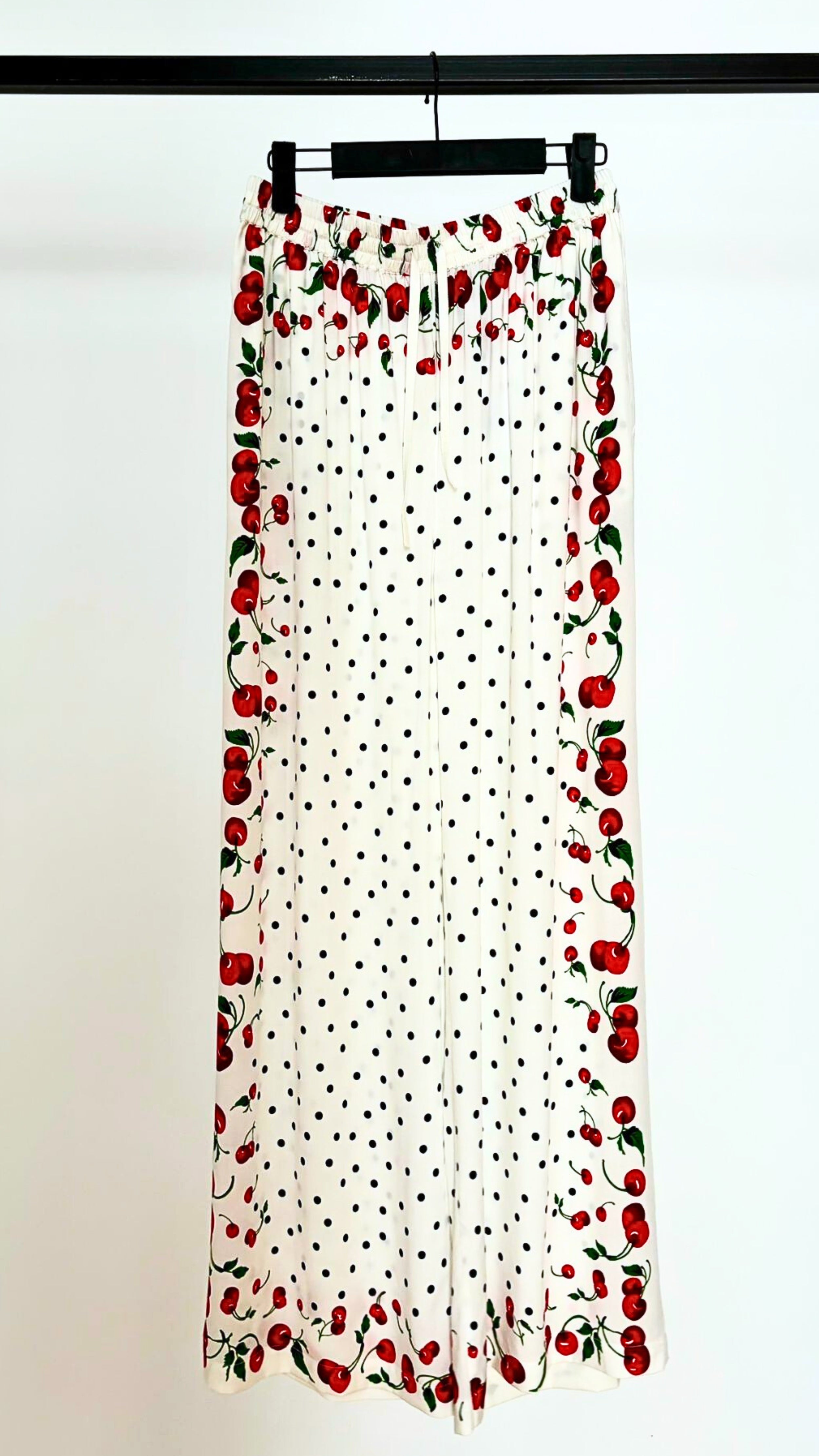 Leslie Amon Jaw String Cherry Pants. White drawstring loose fitting pants with an original cherry and polka dot print. Adjust waist. Shown hanging from the front.