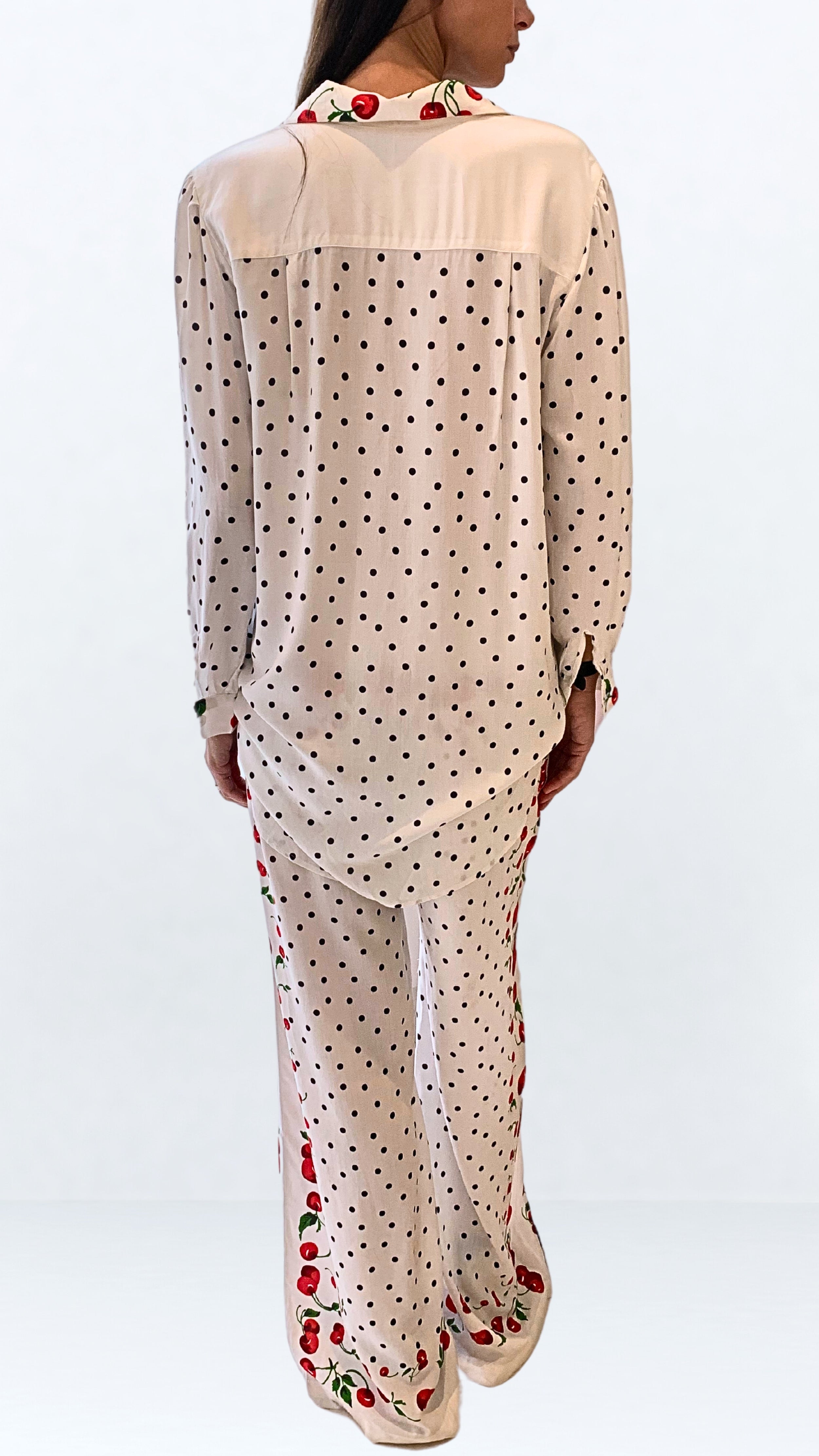 Leslie Amon Oversized Shirt in White Cherry. Oversized blouse in white with red cherry pattern. With button closures up the front, buttoned cuffs and collar. Product photo shown from the back.