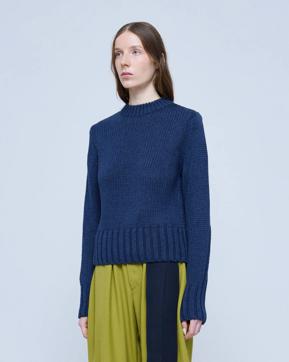 Three-quarter view of the MARTAN Floyd Sweater in anthracite blue, styled with lime trousers