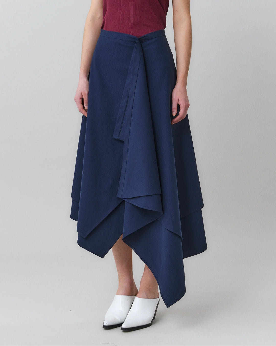 Close-up of draped front panel and self-tie detail on MARTAN Laurie Skirt in navy blue