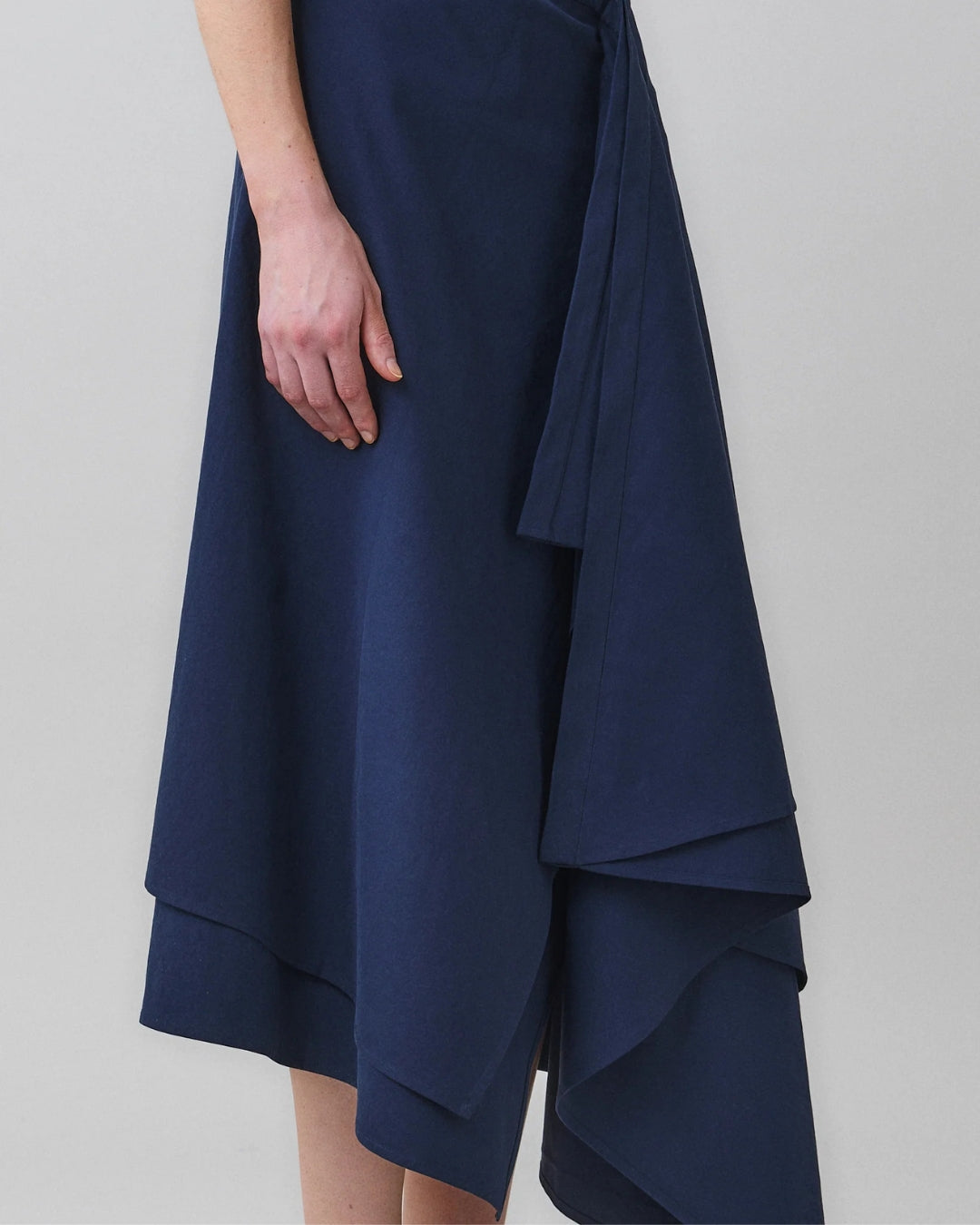 Close-up of draped front panel and self-tie detail on MARTAN Laurie Skirt in navy blue