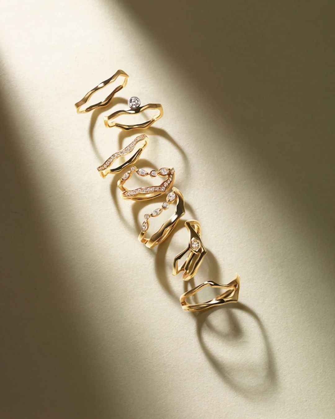 Milamore Kintsugi gold and diamond rings arranged in a line under warm directional light.