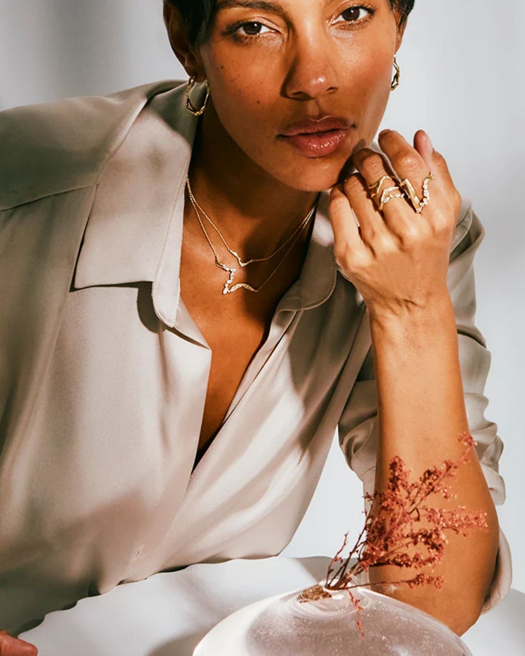 Model wearing layered Milamore gold necklaces with coordinating fine jewelry.