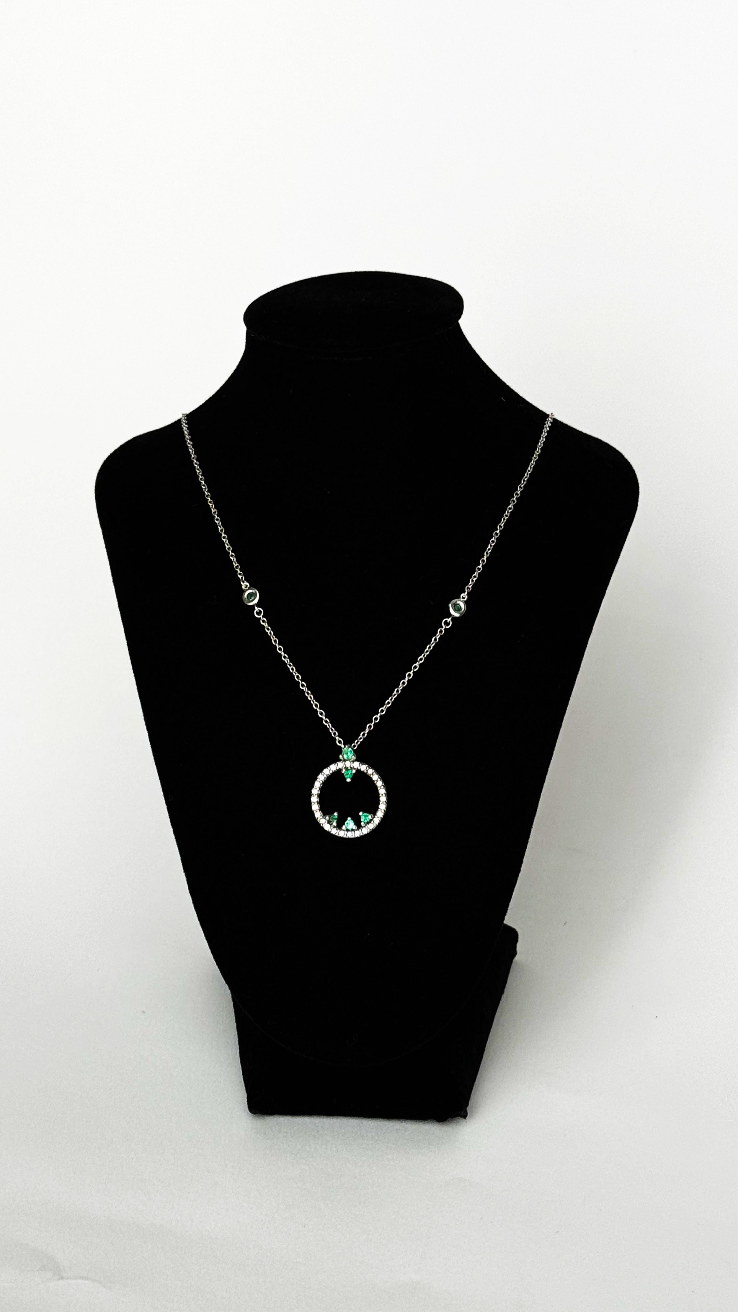 Conde de diamante Minimal Esmeralda Pendant Necklace 18K white gold, art deco-inspired circle design with paved diamond stones and emerald detailing. The 18K white gold chain is accented with emerald links. Photo on necklform