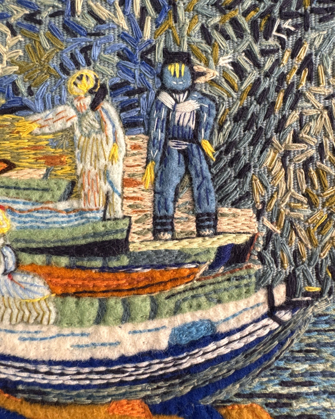 Close-up detail of the hand embroidery on the Bank of the Oise at Auvers clutch, showing the texture and depth of the silk thread and felt appliqué figures and boats.