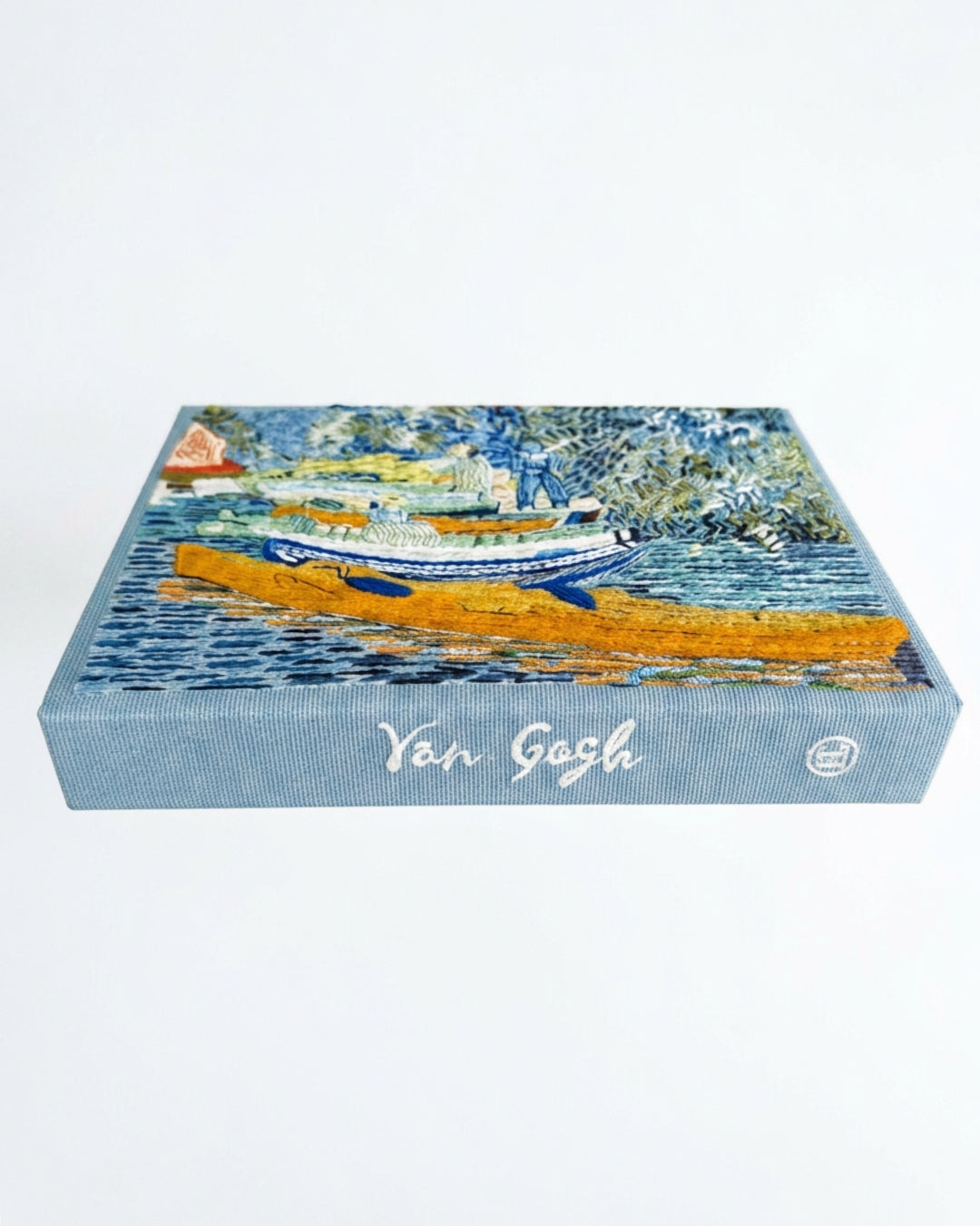Top-down view of the clutch showing the embroidered cover and spine with "Van Gogh" embroidered in white script on the steel-blue cotton ground.