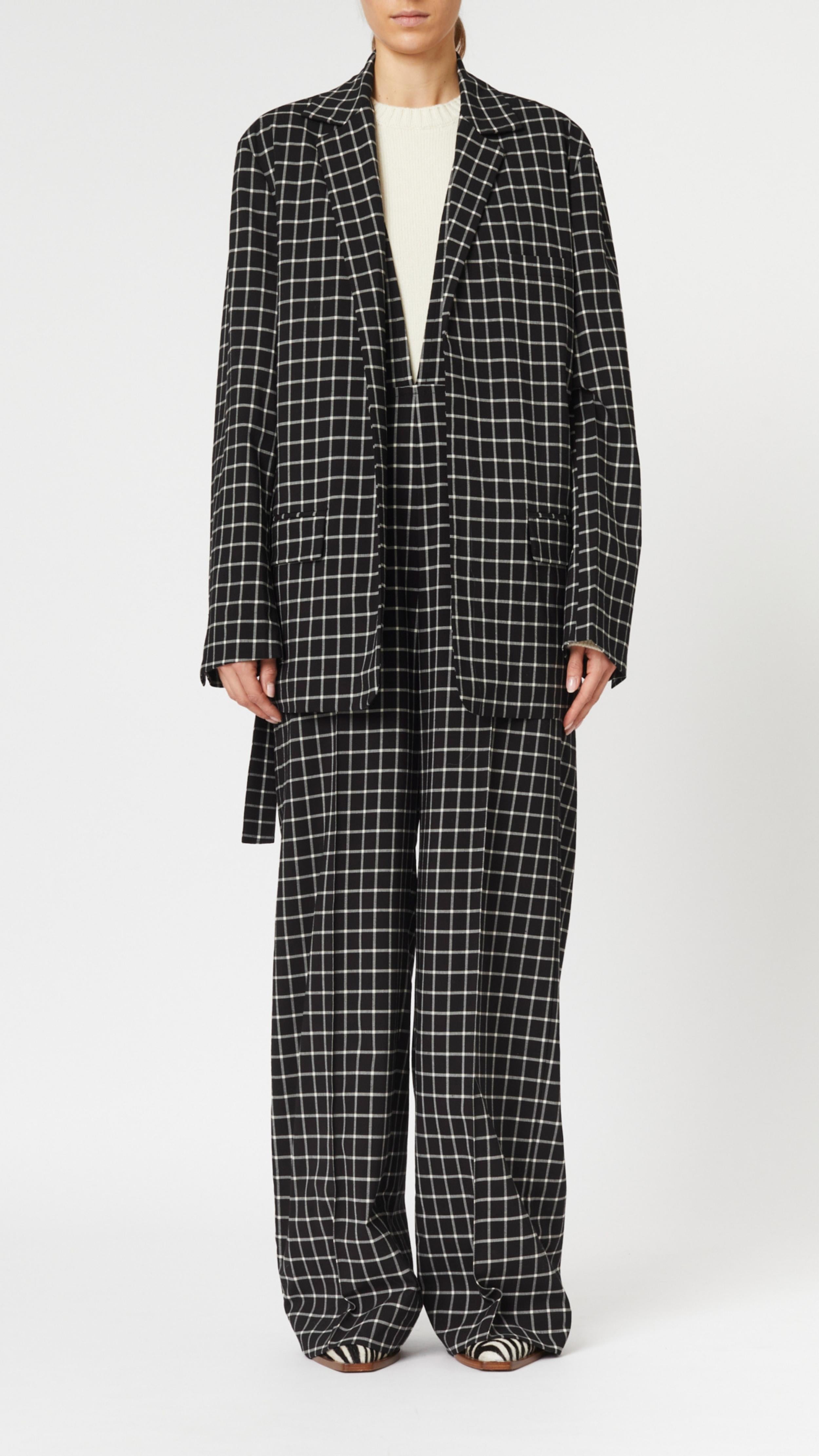 Plan C Checked Black Blazer. Modern suit jacket option in an oversized fit in lightweight wool. Classic black and white check pattern. Shown on model unbelted and open. Facing front.
