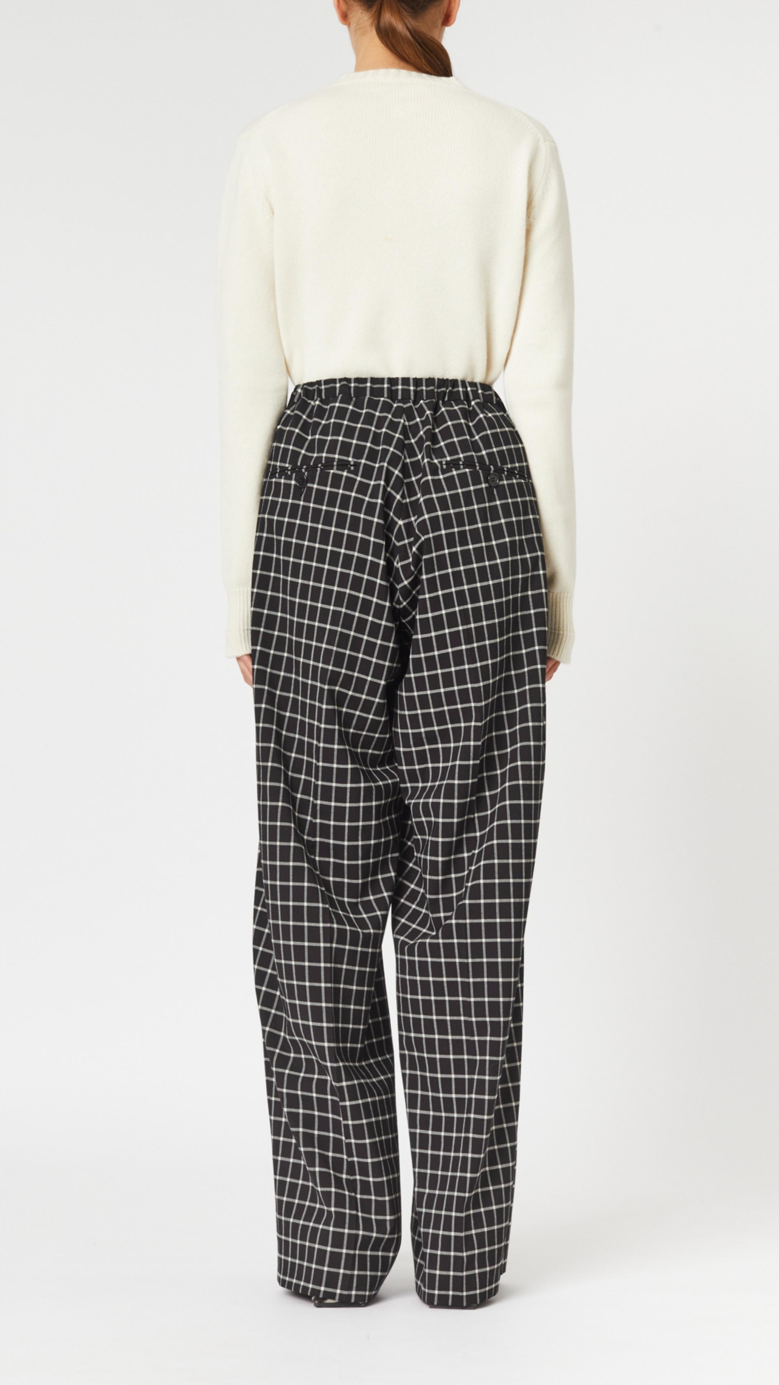 Plan C Checked Black Trousers. Loose fitting suit trousers with a drawstring adjustable waist in a classic black and white check patttern. Modern and oversized style. Shown on model facing back.