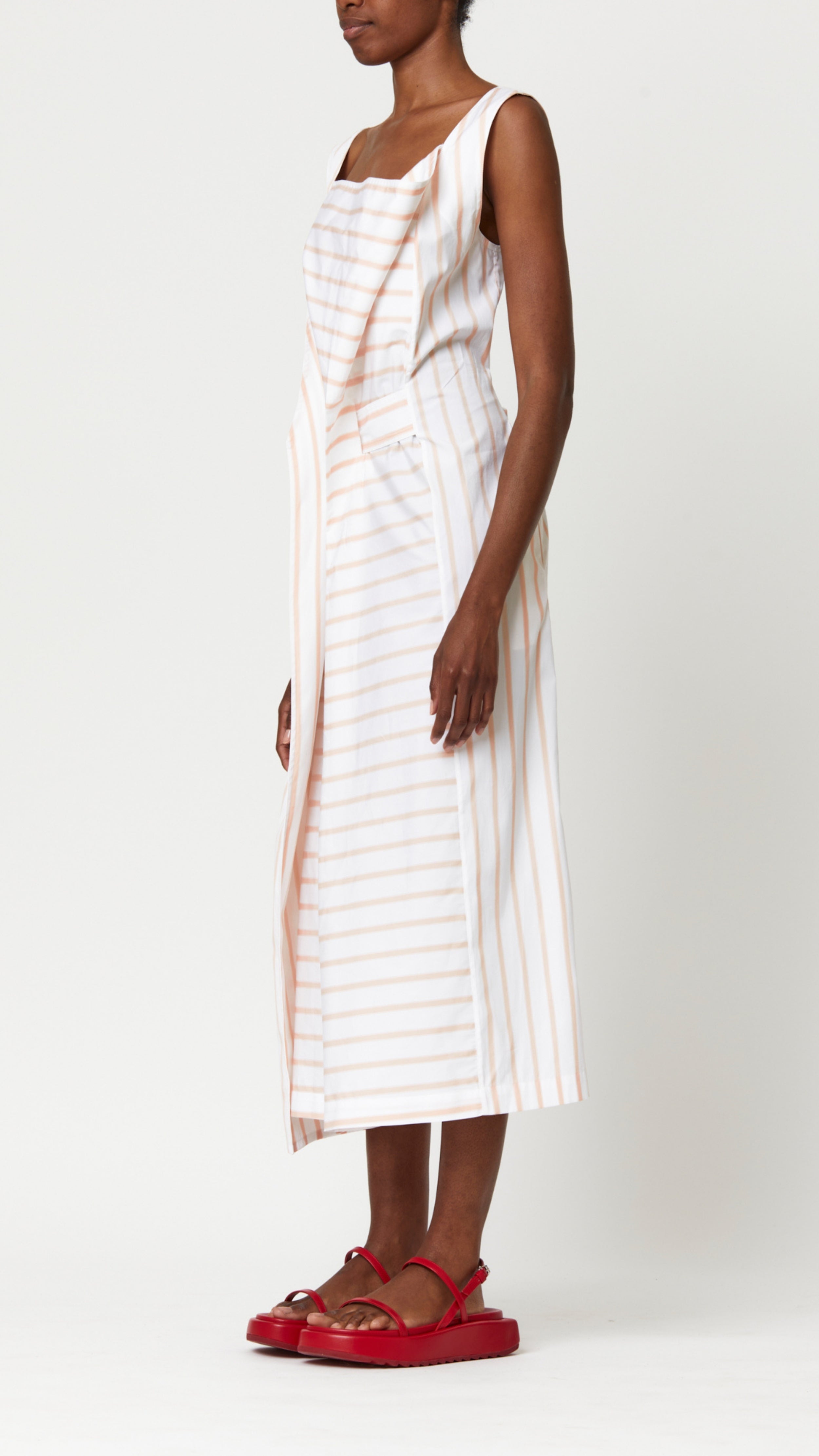 Plan C Cotton Dress in Bellini Stripe Italian-made soft cotton midi dress with bellini stripes. With a square neckline, front draping and cinched waist with fabric belt. Shown on model facing side.
