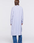 Plan C Striped Cotton Poplin Shirt Dress Classic yet modern shirt dress made from soft cotton poplin in pale blue and white stripes. It has three silver buttons, a collared neckline, long cuffs, and a breast pocket. It's designed with a relaxed fit and side pockets. Shown on model facing back