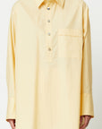 Plan C Eggnog Cotton Shirt A relaxed fit blouse made from light weight cotton in pale yellow and white. With Silver buttons up the front, a chest welt pocket, and a split elongated hem.  Shown on model facing front.