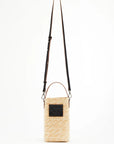 Plan C Handmade Vertical Florentine Straw Pouch A vertical straw bag hand crafted by Florentine artisans with a Bianca illustrated leather label on the front. It has an adjustable shoulder strap and flat handles in soft black leather. It has an internal cotton pouch with rope drawstring. Shown from the front view with the long adjustable strap.