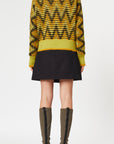 Plan C Long Sleeve Jacquard Knit Sweater.Ppistachio, black and ochre colors in a V chevron print. Red pop of color at the collar. Photo shown on model facing to the back..