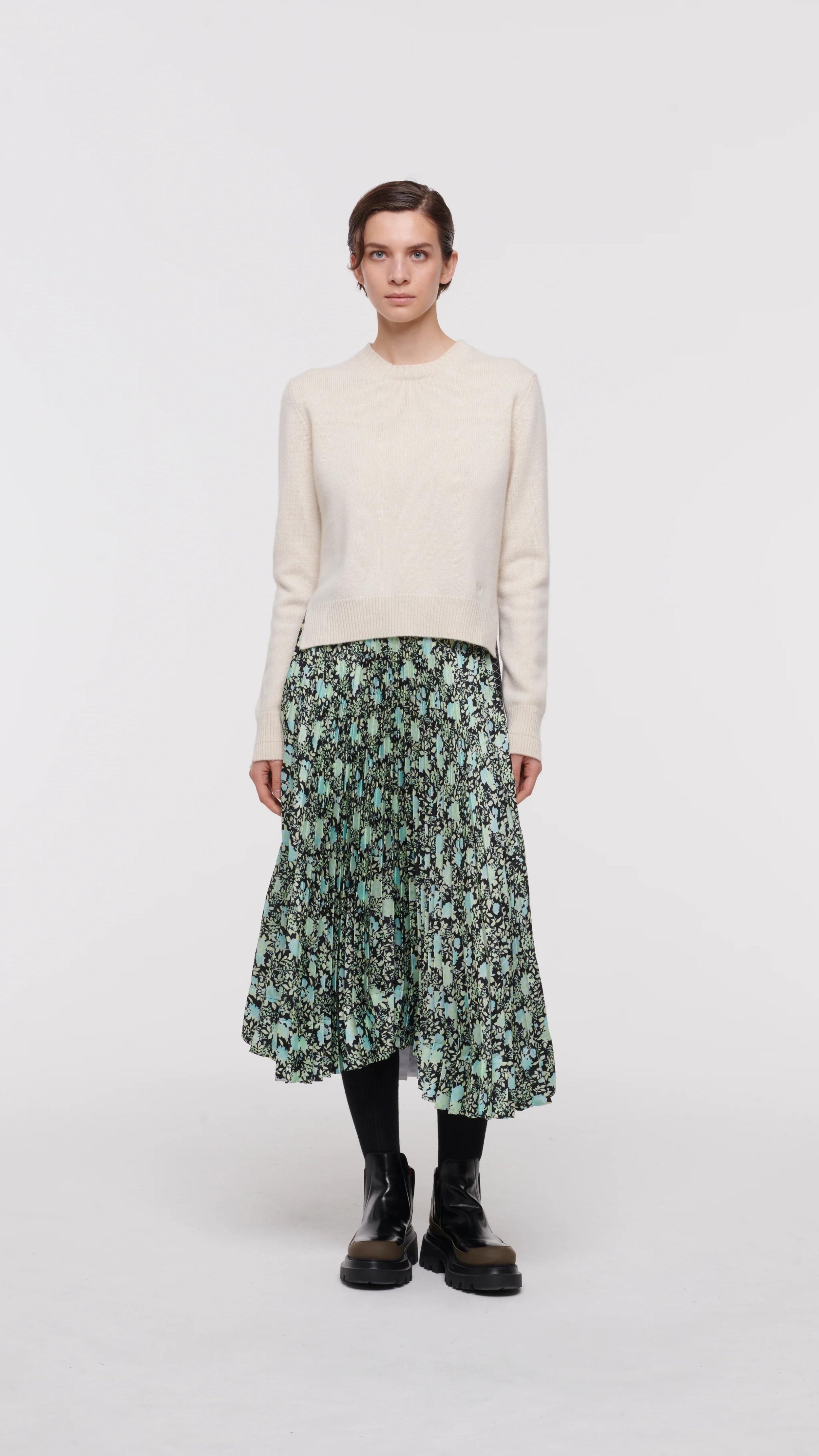 Plan C Pleated Midi Skirt in Backlit Dahlia Print.  Featuring alternating geometrical and flower prints, a slender pleated front, and larger pleating on the back, this skirt falls to a midi length asymmetric hem. The elasticated waist offers perfect comfort and easy fitting. Model wearing the skirt facing front.