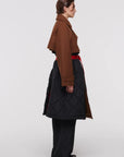Plan C Quilted Double Breasted Coat. Black quilted culpro and cotton interior with a chestnut brown wool over piece at the collar, sleeves and waist. Highlighted by a wrap around long belt at the waist. Show from the side view.
